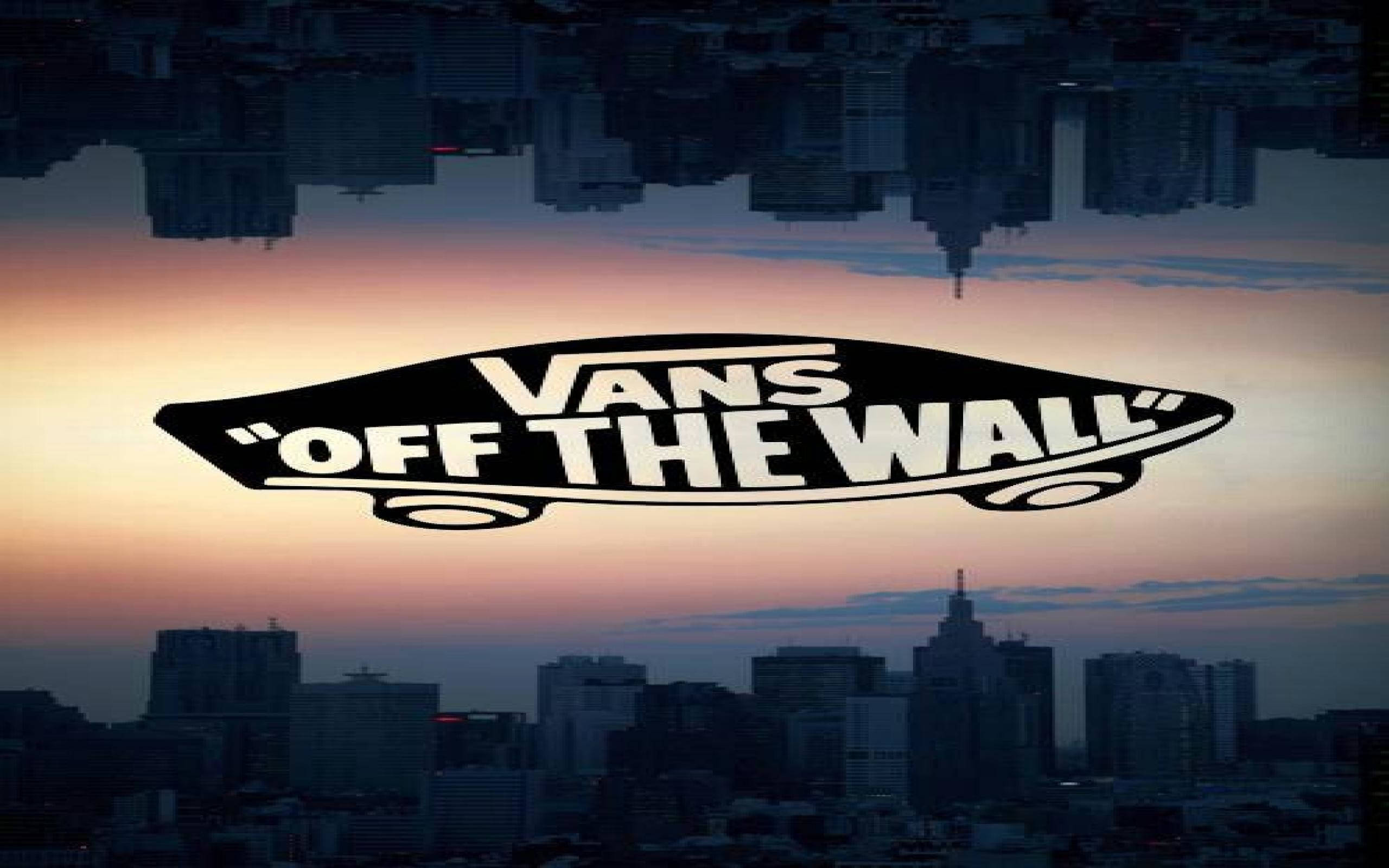 Vans Off The Wall 桌布 壁紙 — Vans Off The Wall 標誌漂浮在日落時分的城市天際線上方，其倒影映照在下方水面上。