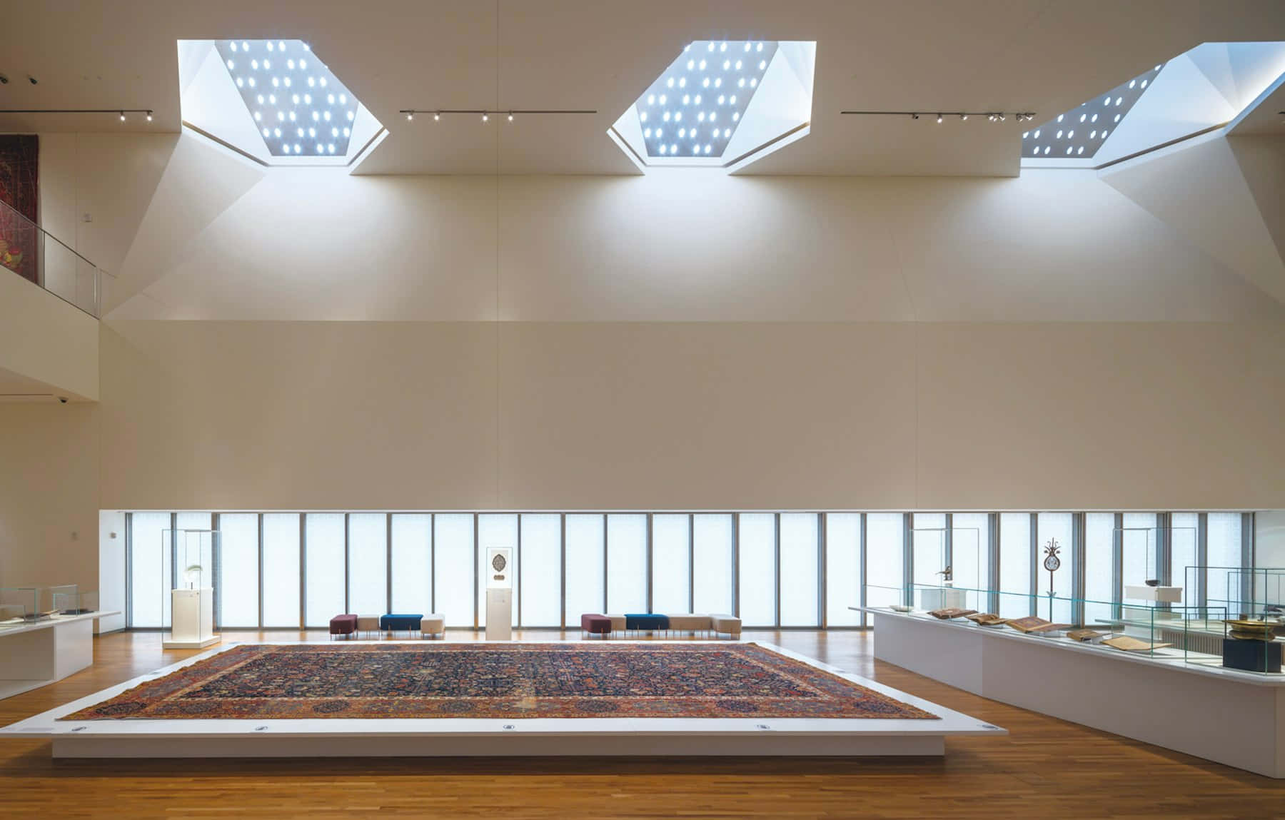 Aga Khan Museum 桌布 壁紙 — 寬敞的現代博物館大廳，天窗照亮了高台上一張大型華麗地毯。