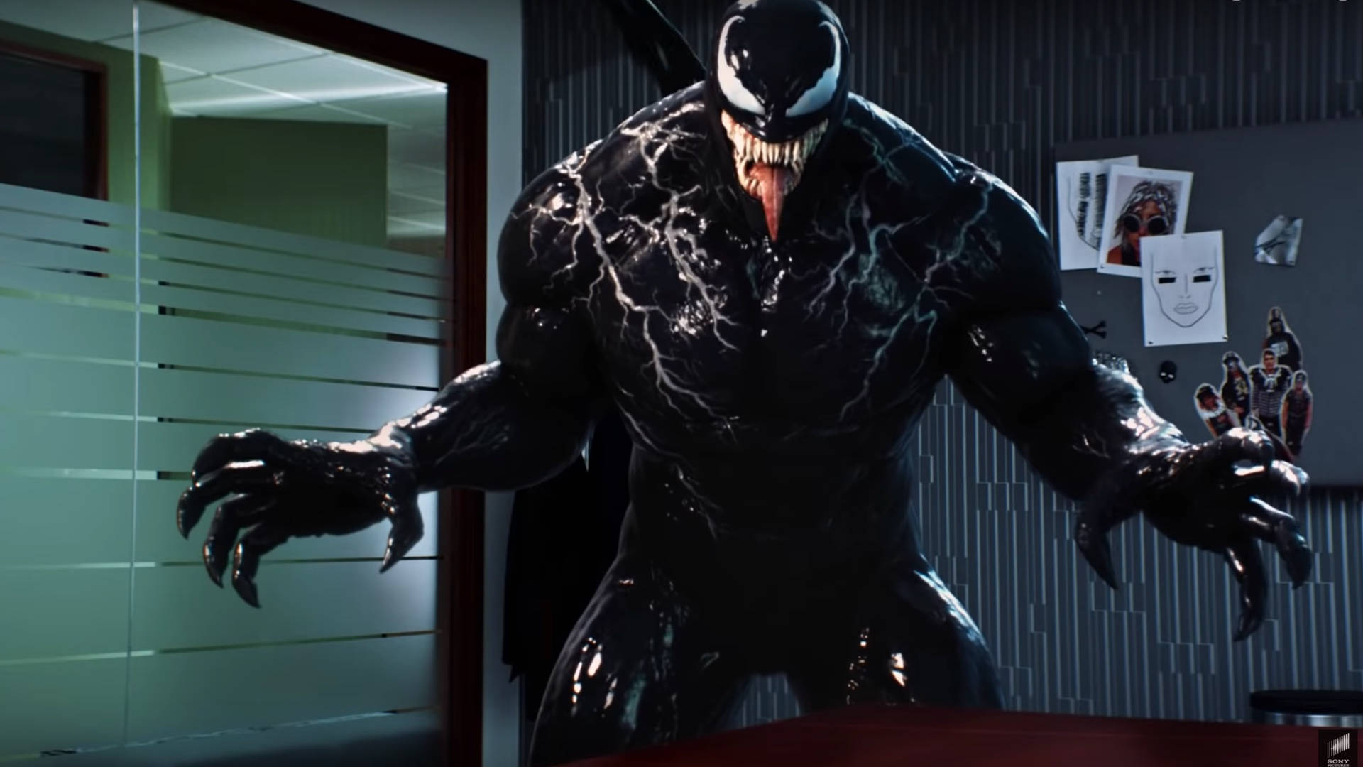 猛毒 桌布 壁紙 — Venom 在辦公室中威嚇地站立，他的黑色共生體套裝在螢光燈下閃閃發光。