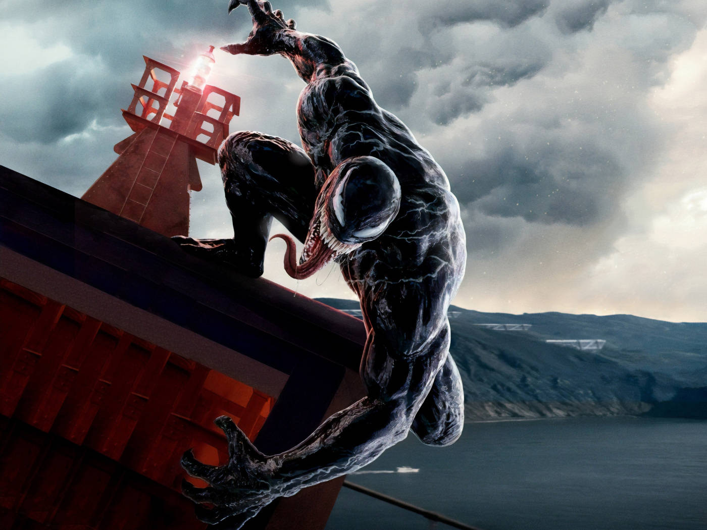 Venom Movie 桌布 壁紙 — Venom 蹲在紅色燈塔頂上，背景是暴風雨的天空，露出鋸齒狀的牙齒和發光的眼睛。