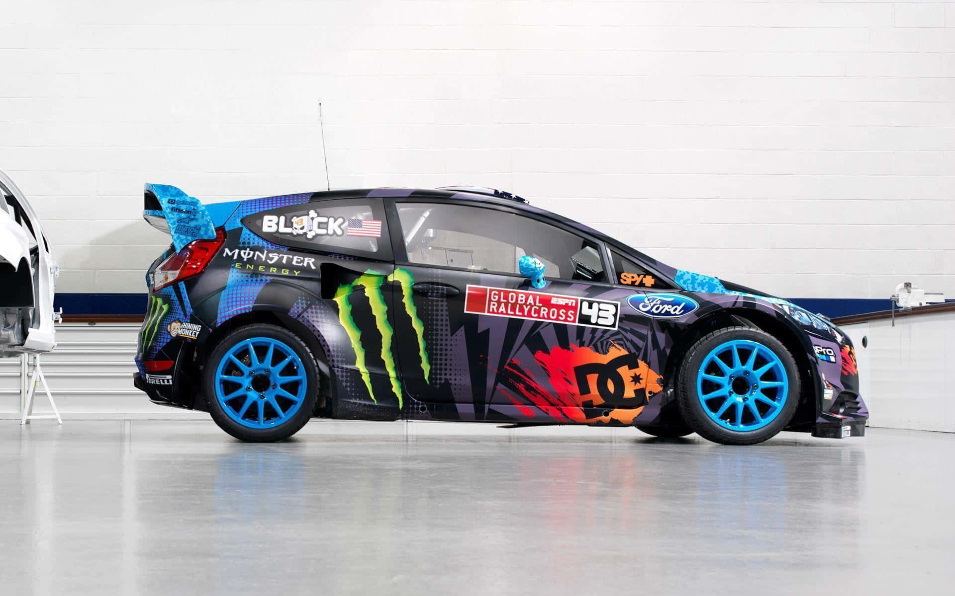Ford Fiesta 桌布 壁紙 — 一輛充滿活力的黑色拉力賽車，配備藍色輪圈和Monster Energy貼紙，停放在室內拋光地板上。