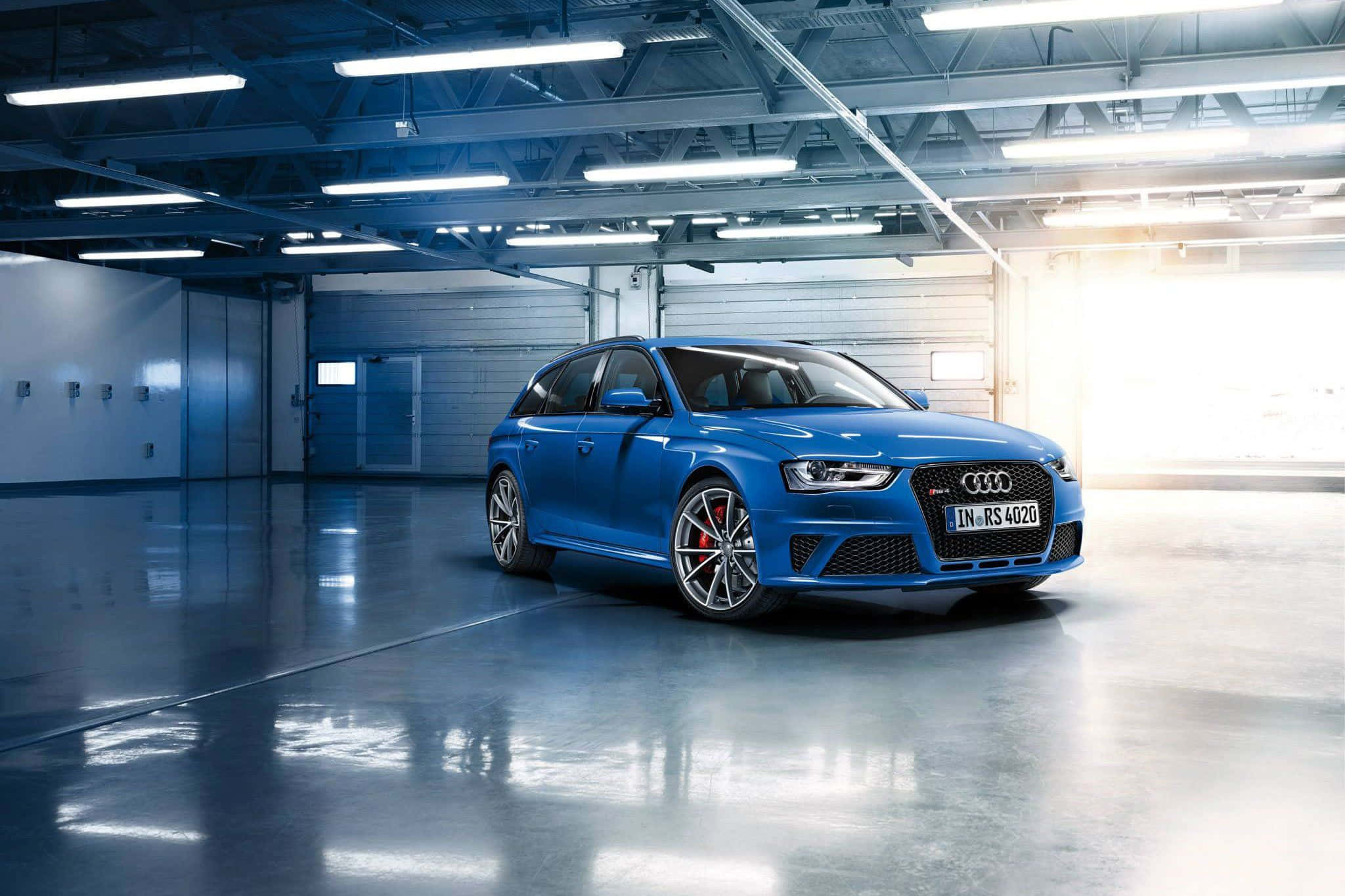 Audi Rs5 桌布 壁紙 — 一輛充滿活力的藍色奧迪RS4旅行車在寬敞的混凝土車庫中，在工業照明下閃閃發光。