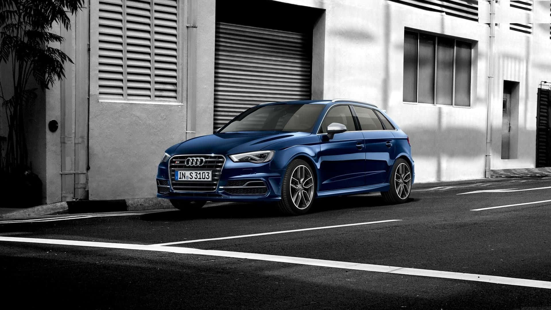 Audi S3 桌布 壁紙 — 一輛充滿活力的藍色奧迪S3旅行車停泊在陽光明媚的城市街道上，背景是單色工業建築。