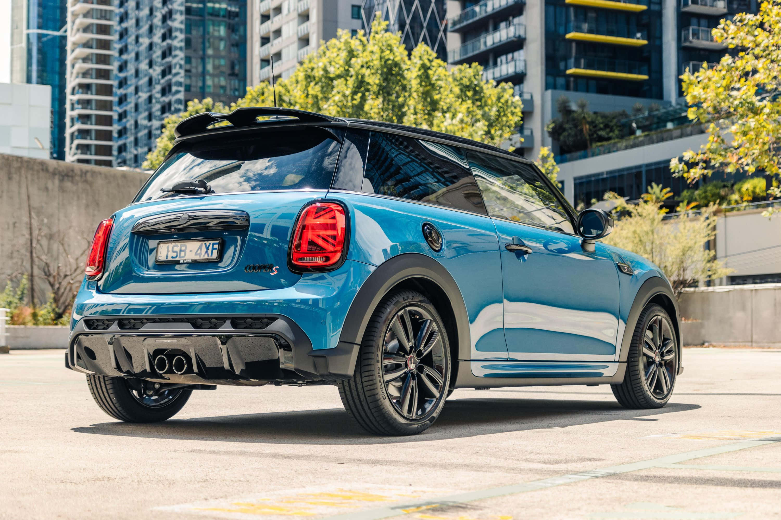 Mini Cooper S 桌布 壁紙 — 一輛充滿活力的藍色MINI Cooper停放在城市街道上，背景有現代建築和綠樹。