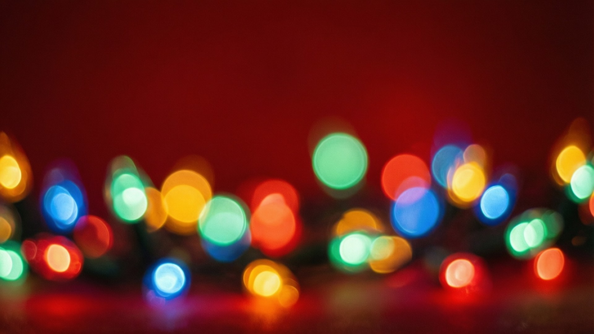 Christmas Lights Bokeh 壁紙 — 深紅色背景上柔和發光的彩色節日燈光營造出充滿活力的散景效果。