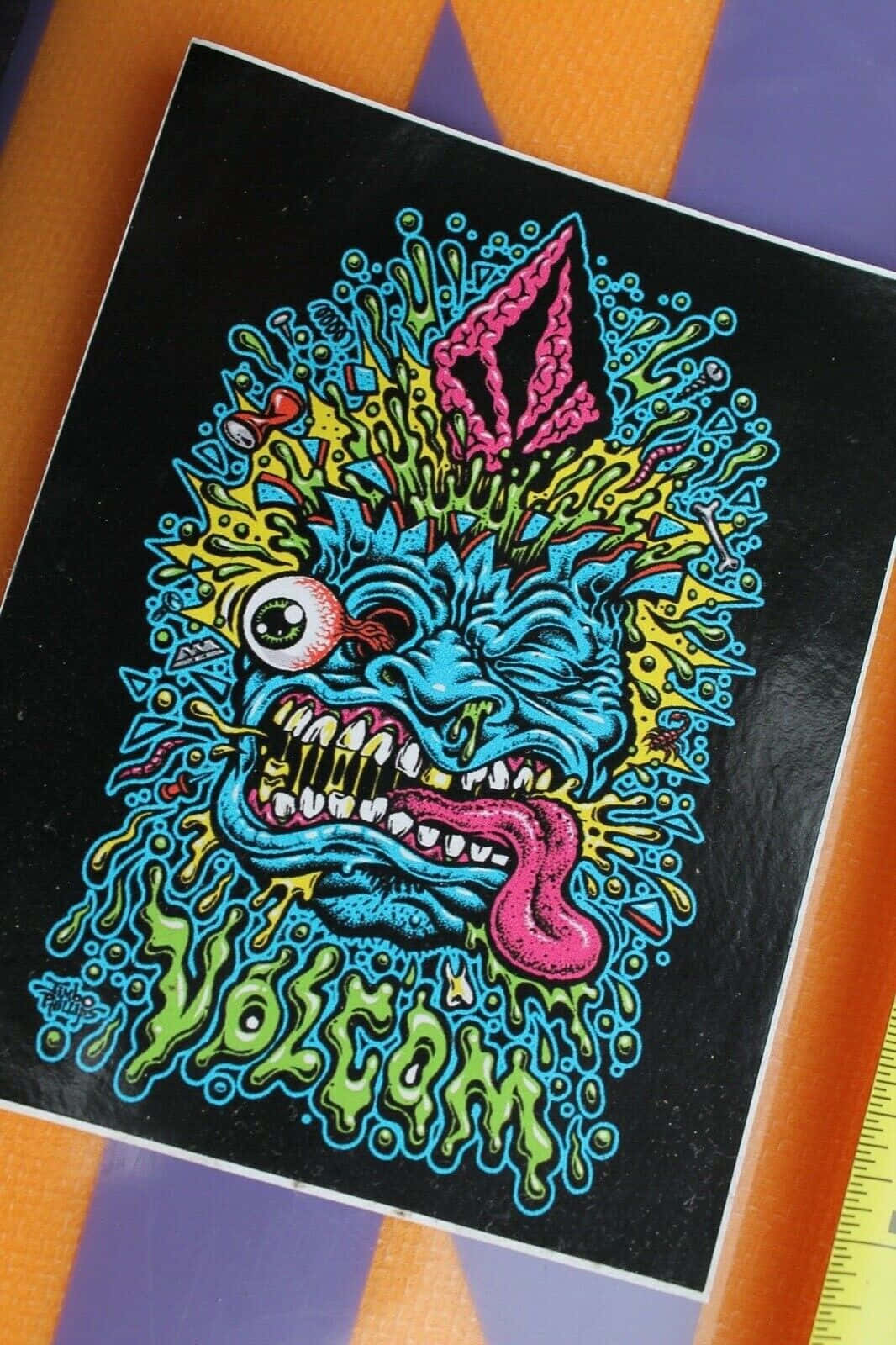 壁紙 — 一個充滿活力的卡通怪物，單眼和粉紅色舌頭，從黑色背景中以霓虹色彩爆發出來。