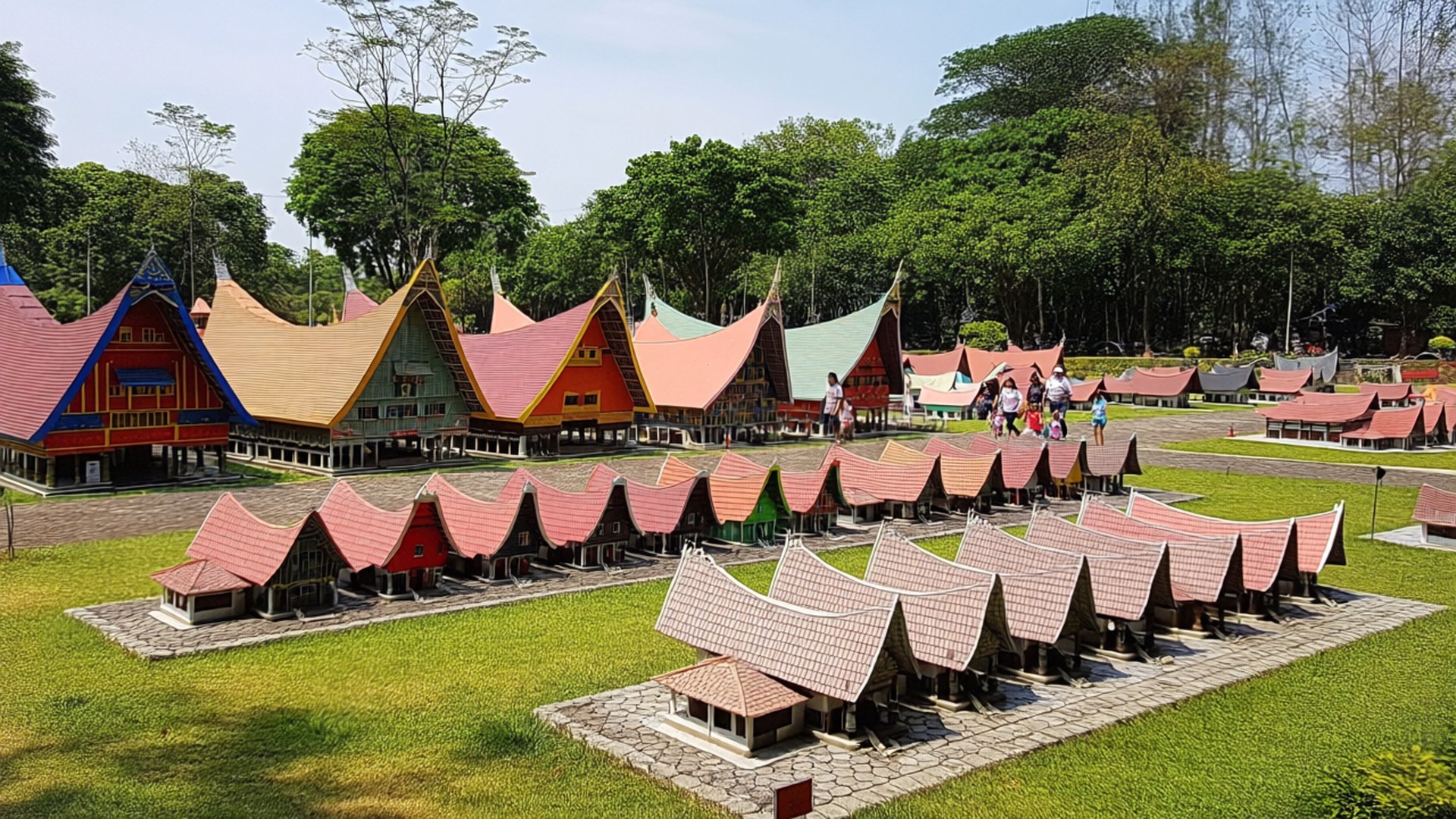 Taman Mini Indonesia 壁紙 — 充滿活力的傳統印尼房屋收藏，色彩繽紛的尖頂屋頂整齊排列在陽光明媚的綠色草坪上。