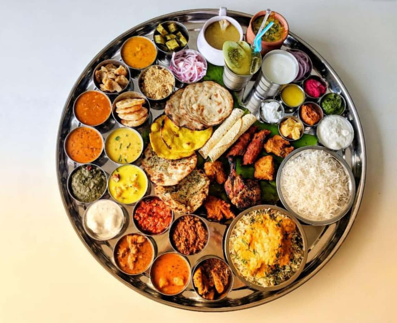 Thali 桌布 壁紙 — 一個充滿活力的印度塔利拼盤，色彩繽紛的咖哩、麵包、米飯和酸辣醬整齊排列在閃亮的金屬托盤上。