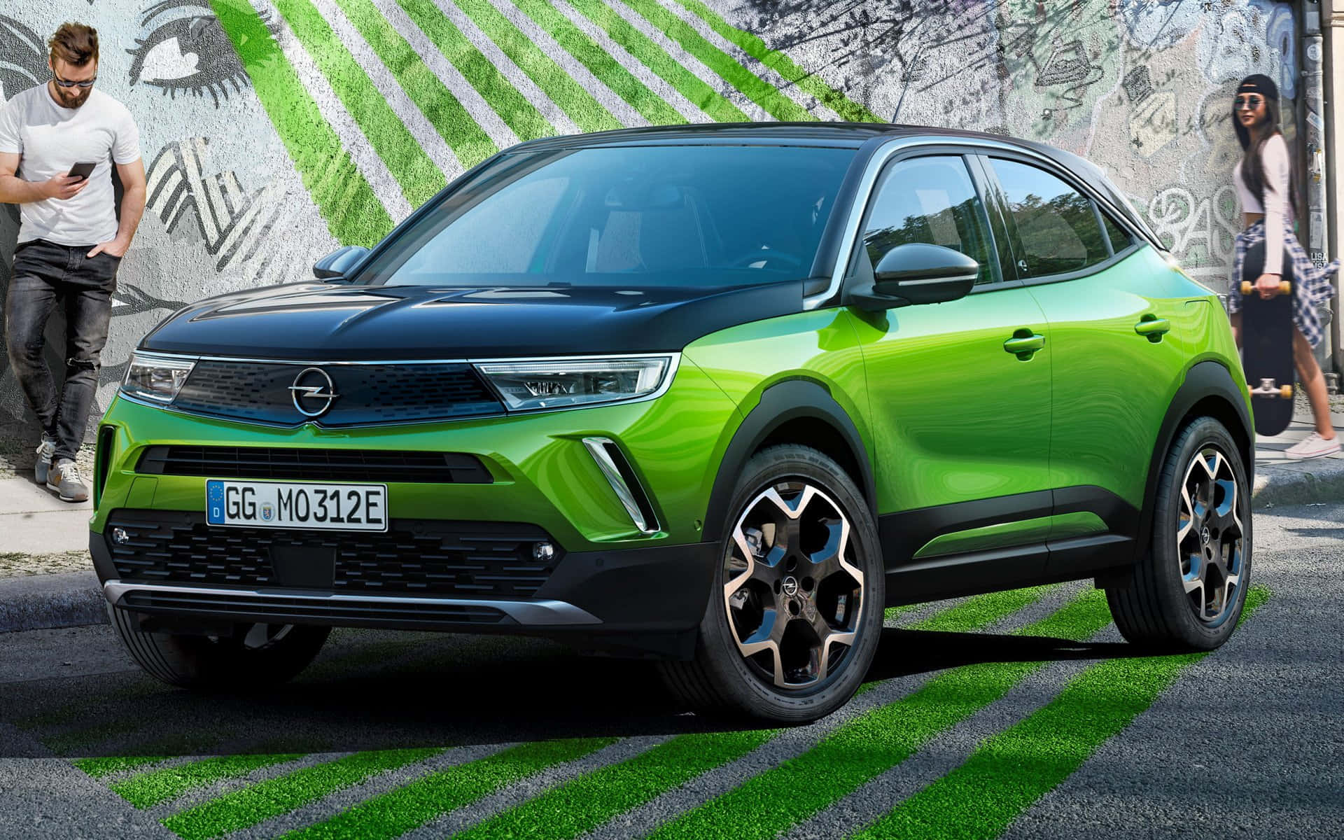 Opel Mokka 桌布 壁紙 — 一輛充滿活力的萊姆綠色電動Opel跨界車停在佈滿塗鴉的城市街道上，附近有行人。