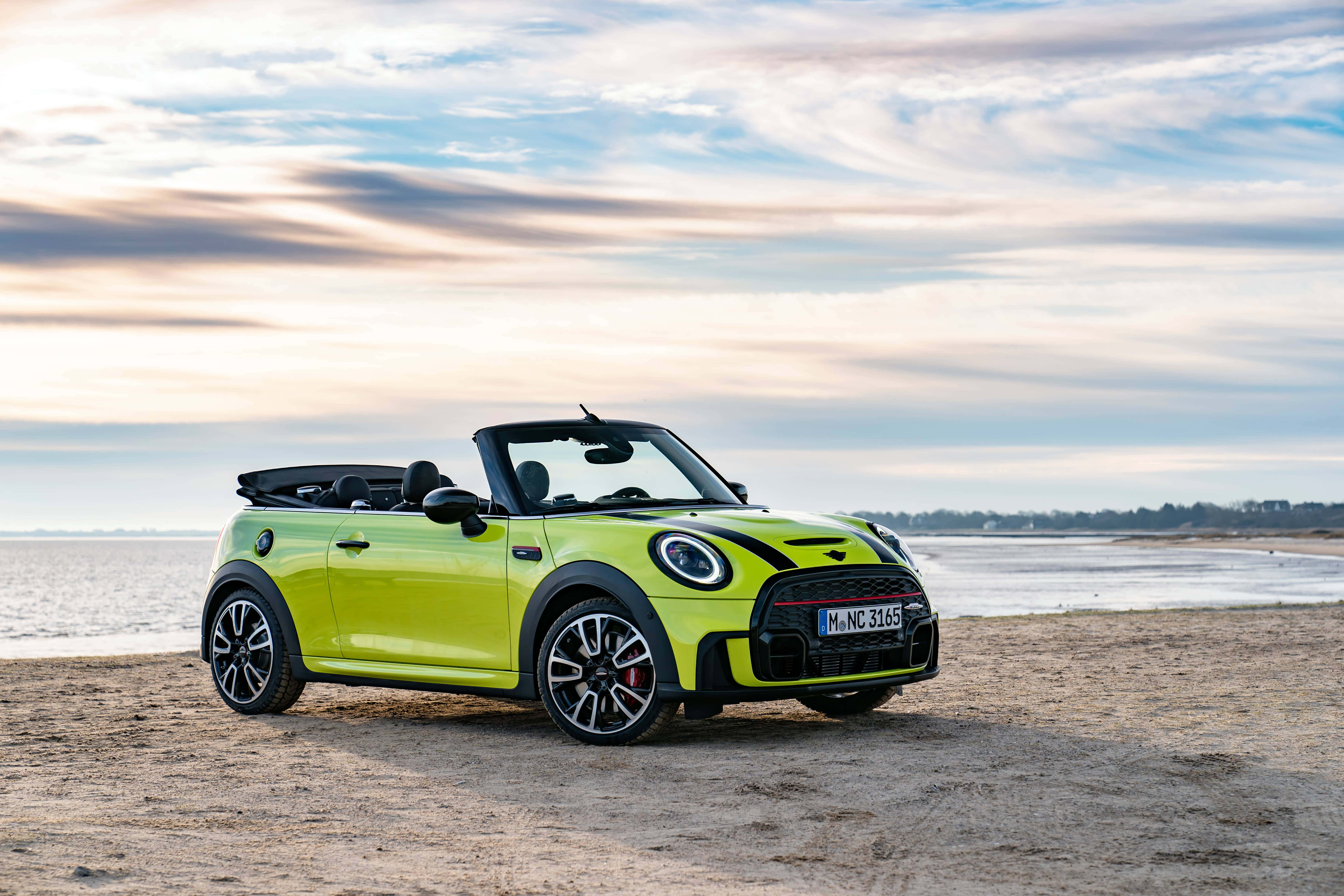 Mini Cooper Convertible 桌布 壁紙 — 一輛充滿活力的萊姆綠色MINI敞篷車在日落時分停泊在沙灘上，天空呈現柔和粉彩色調。