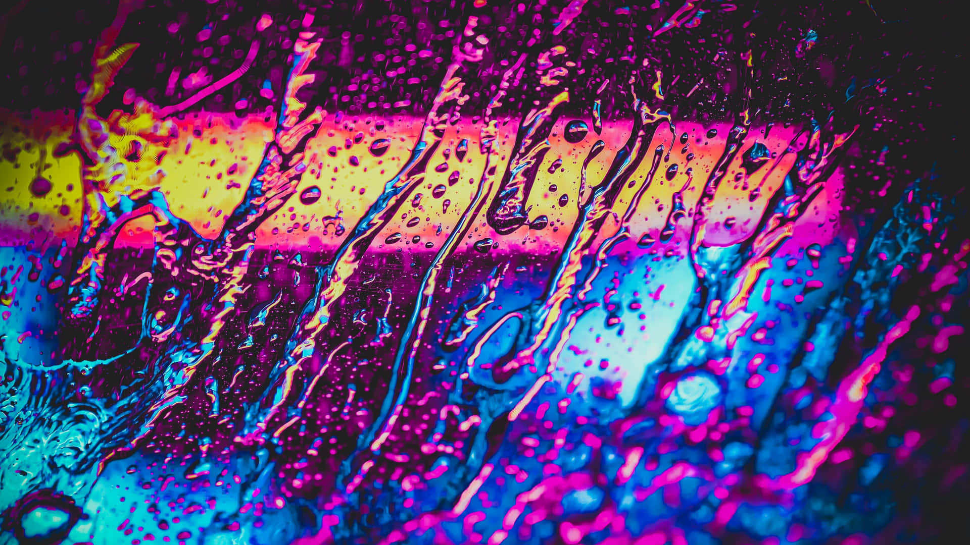  壁紙 — 鮮豔的霓虹色彩在潮濕的表面上劃過，雨滴將光線折射成粉紅、藍色和黃色的電光色調。