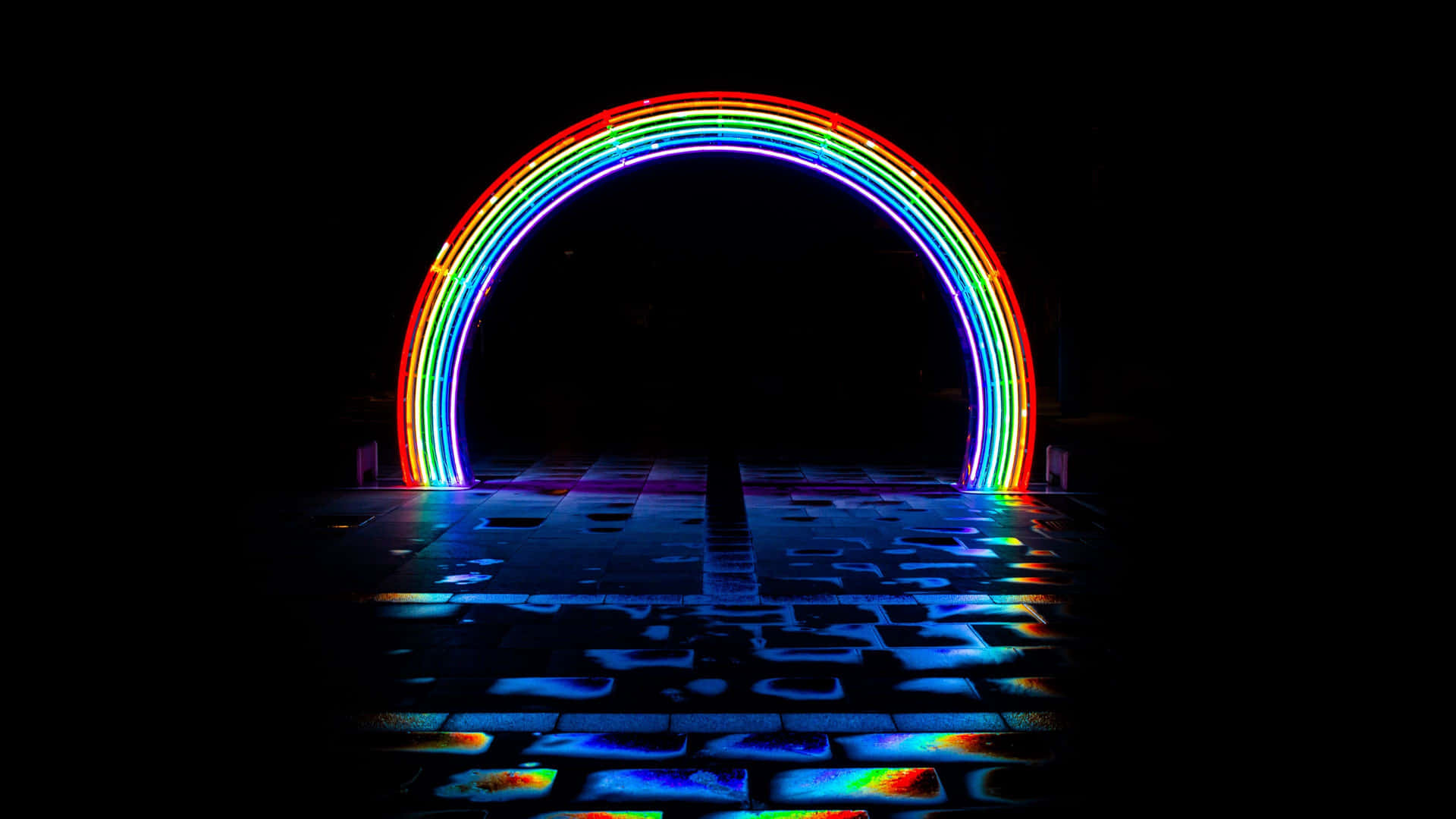  壁紙 — 一道充滿活力的霓虹彩虹拱門在黑色夜空中發光，在潮濕的瓷磚地板上投射出色彩繽紛的倒影。
