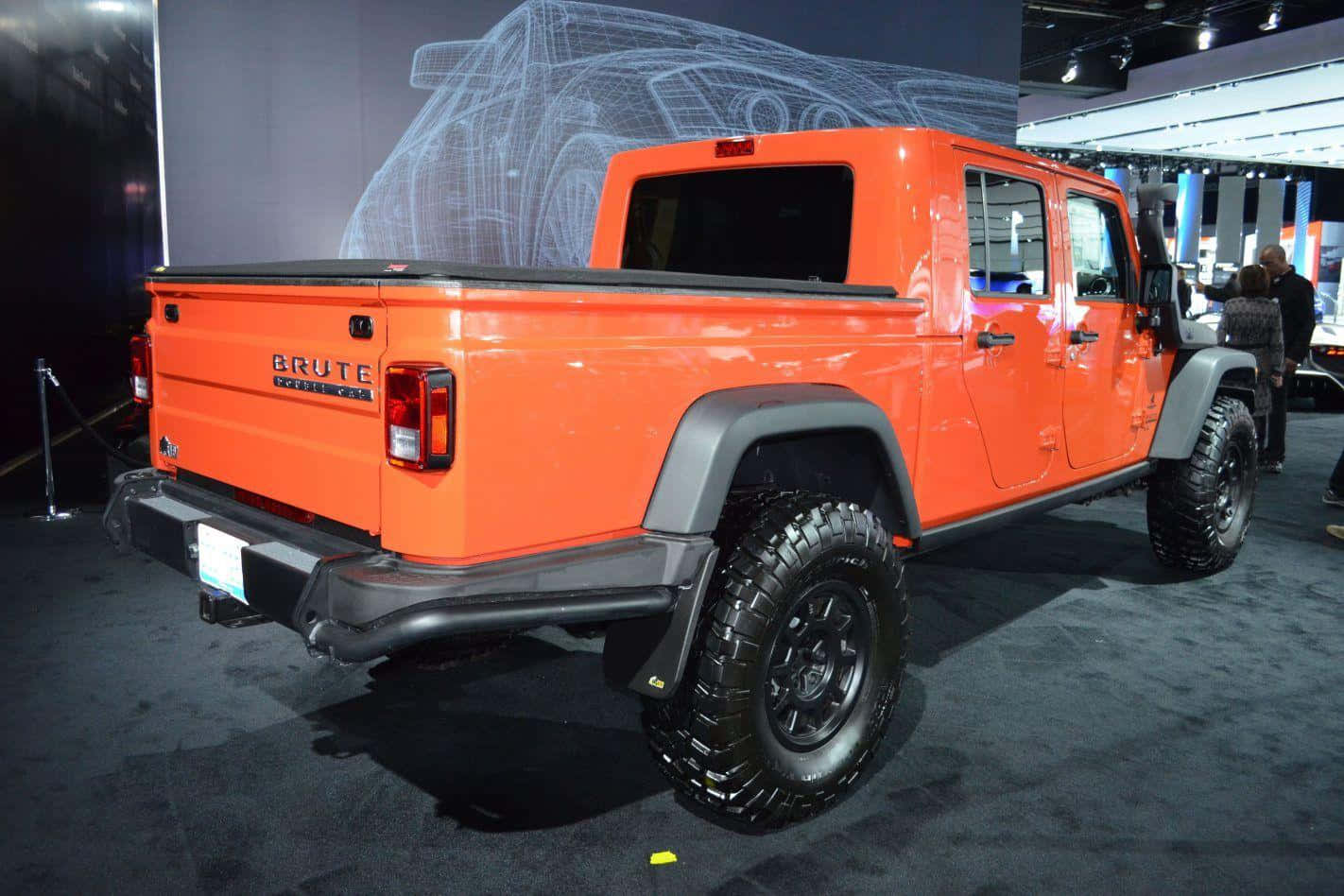 Jeep Gladiator 桌布 壁紙 — 充滿活力的橙色 Brute 皮卡車在車展上展出，背景為線框，附近有與會者。