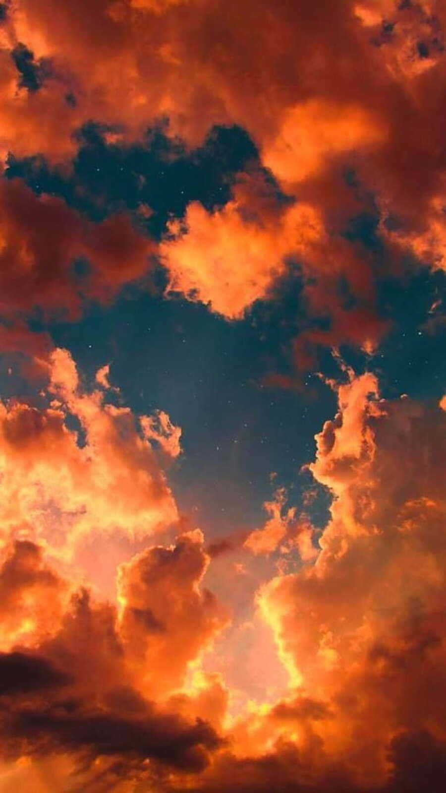  壁紙 — 鮮豔的橙色雲彩在點綴著星星的深青色天空中戲劇性地旋轉。