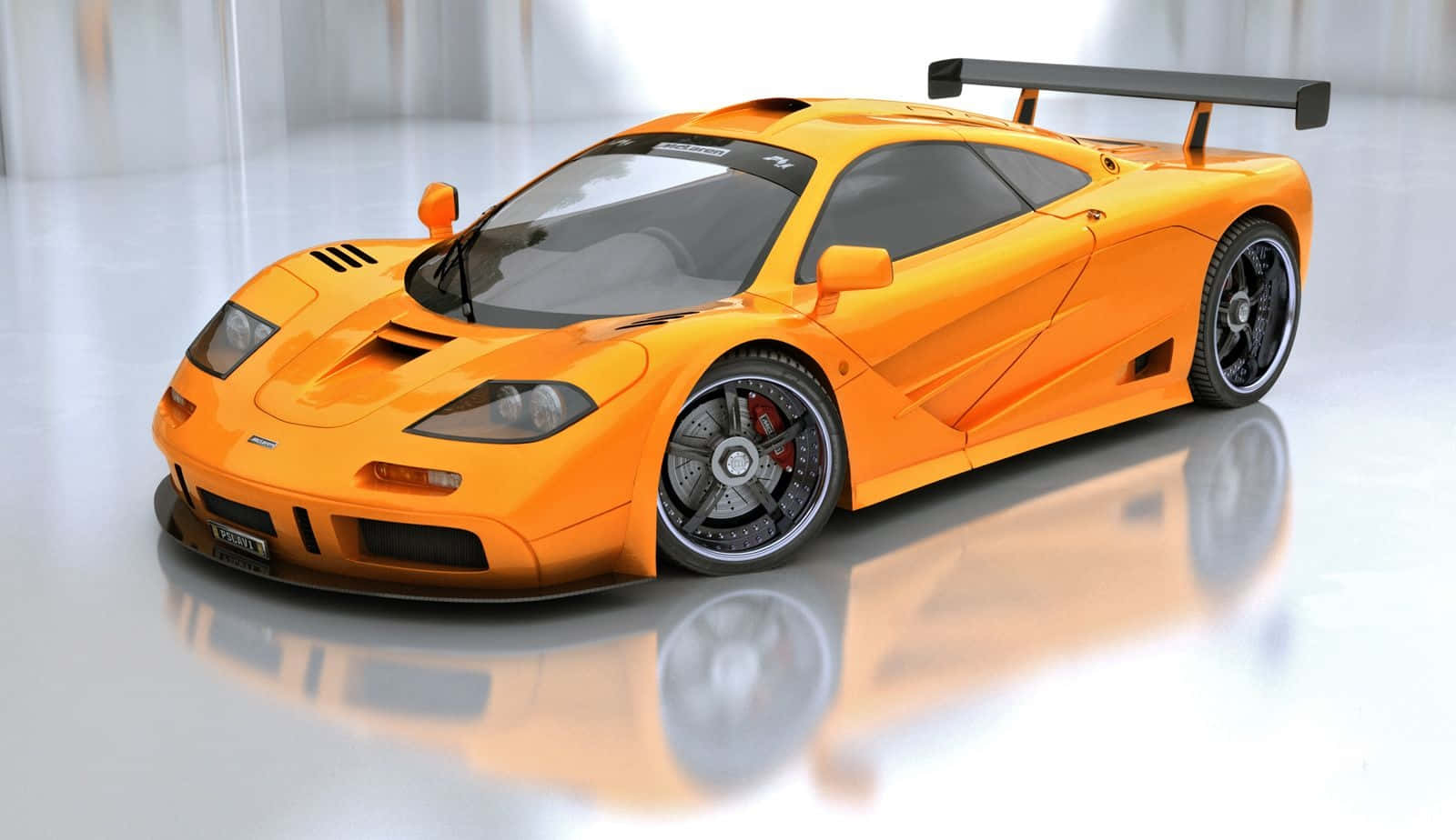 Mclaren F1 桌布 壁紙 — 一輛充滿活力的橙色McLaren F1超級跑車，帶有黑色飾邊和大型尾翼，停在極簡主義工作室的反射白色地板上。
