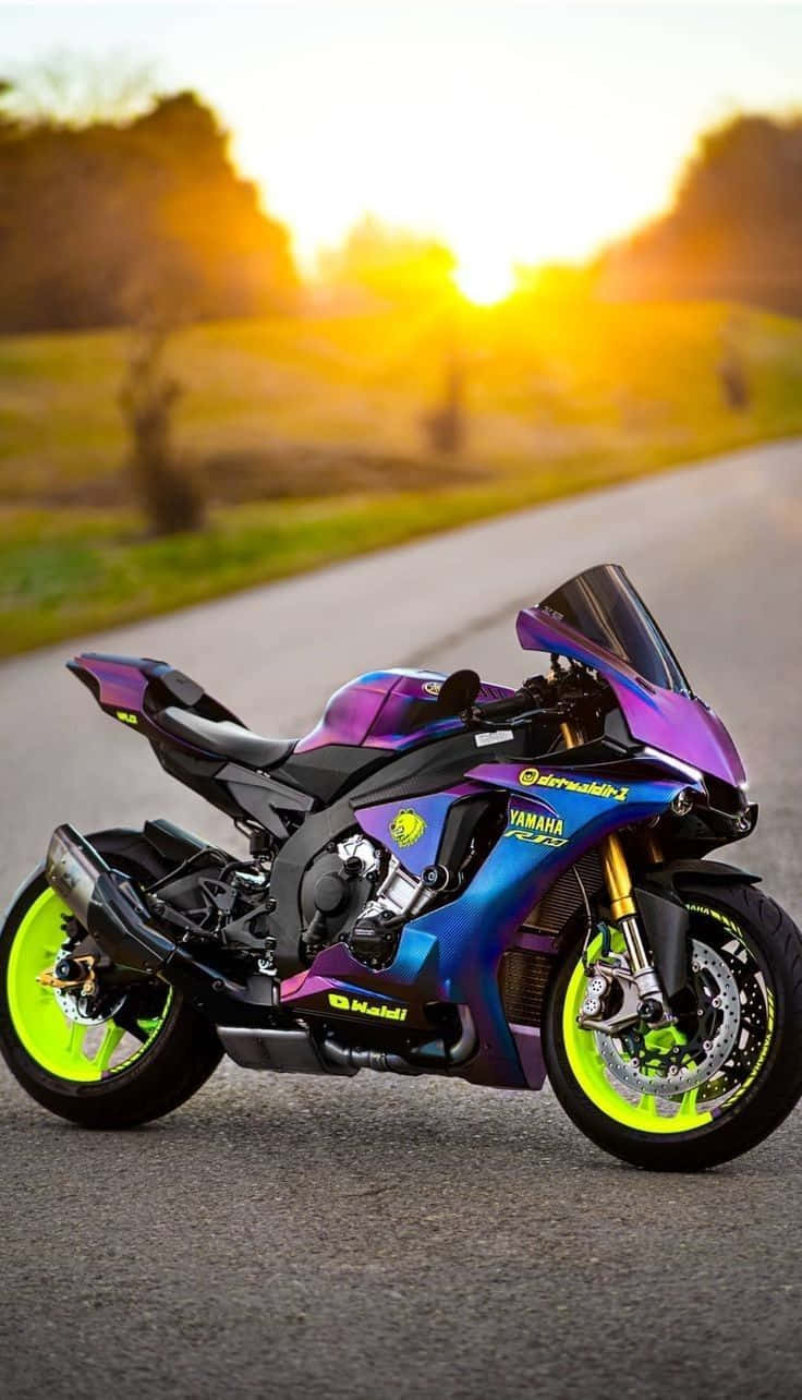  壁紙 — 一輛充滿活力的紫色和藍色Yamaha運動型摩托車，配備螢光綠色輪胎，停泊在金色日落時分的道路上。