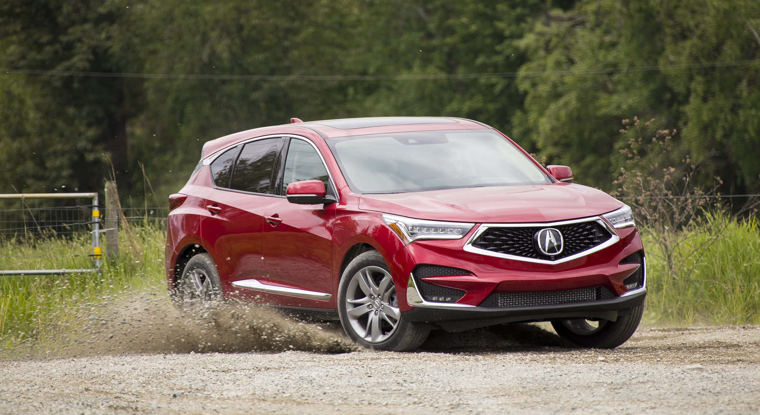 Acura Rdx 桌布 壁紙 — 一輛鮮紅色的Acura SUV在碎石路上行駛，在樹木茂密的鄉村環境中揚起灰塵。
