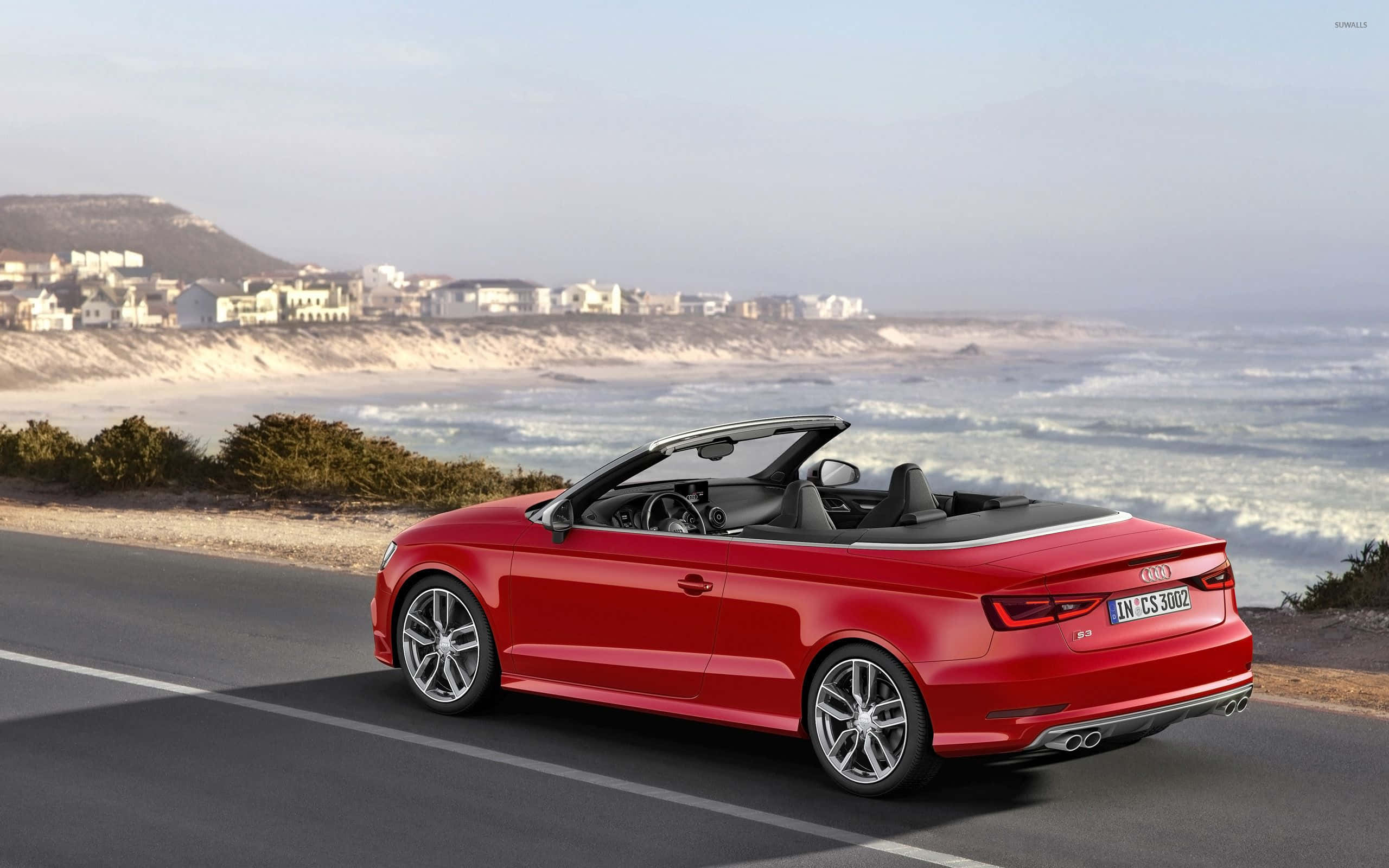 Audi S3 桌布 壁紙 — 一輛充滿活力的紅色奧迪敞篷車沿著海岸道路行駛，背景是海浪和山坡小鎮。