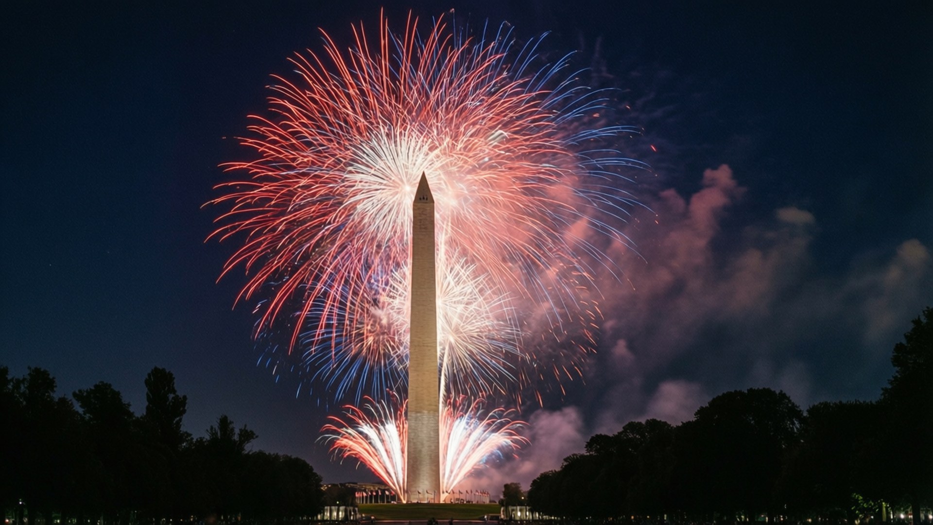 Fourth of July Fireworks 壁紙 — 鮮豔的紅色、藍色和白色煙火在夜間華盛頓紀念碑後方綻放出耀眼的光芒。