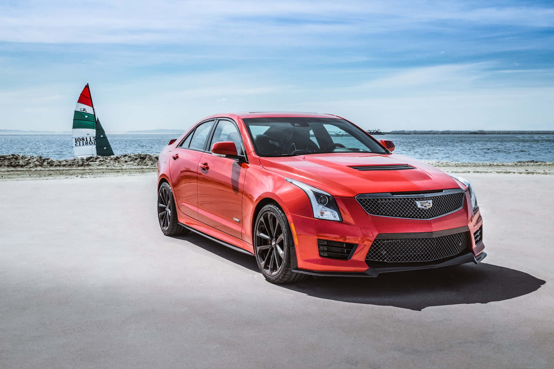 Cadillac Ats 桌布 壁紙 — 一輛鮮紅色的Cadillac ATS-V跑車停泊在混凝土碼頭上，背景有帆船，天空清澈湛藍。