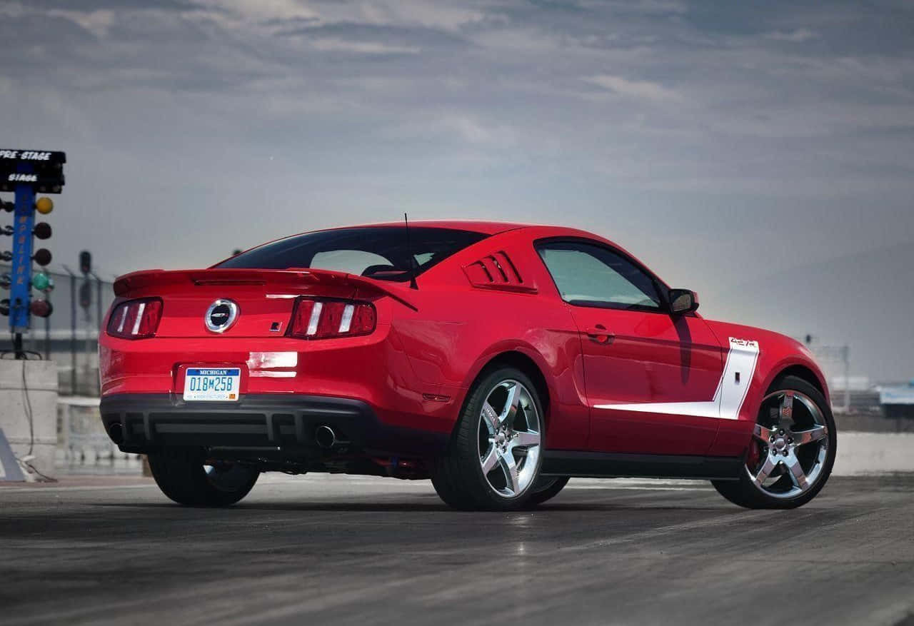 Ford Mustang Roush 桌布 壁紙 — 一輛鮮紅色的福特野馬GT Raptor在陰天之下蓄勢待發於直線加速賽道上，背景可見賽車燈光。