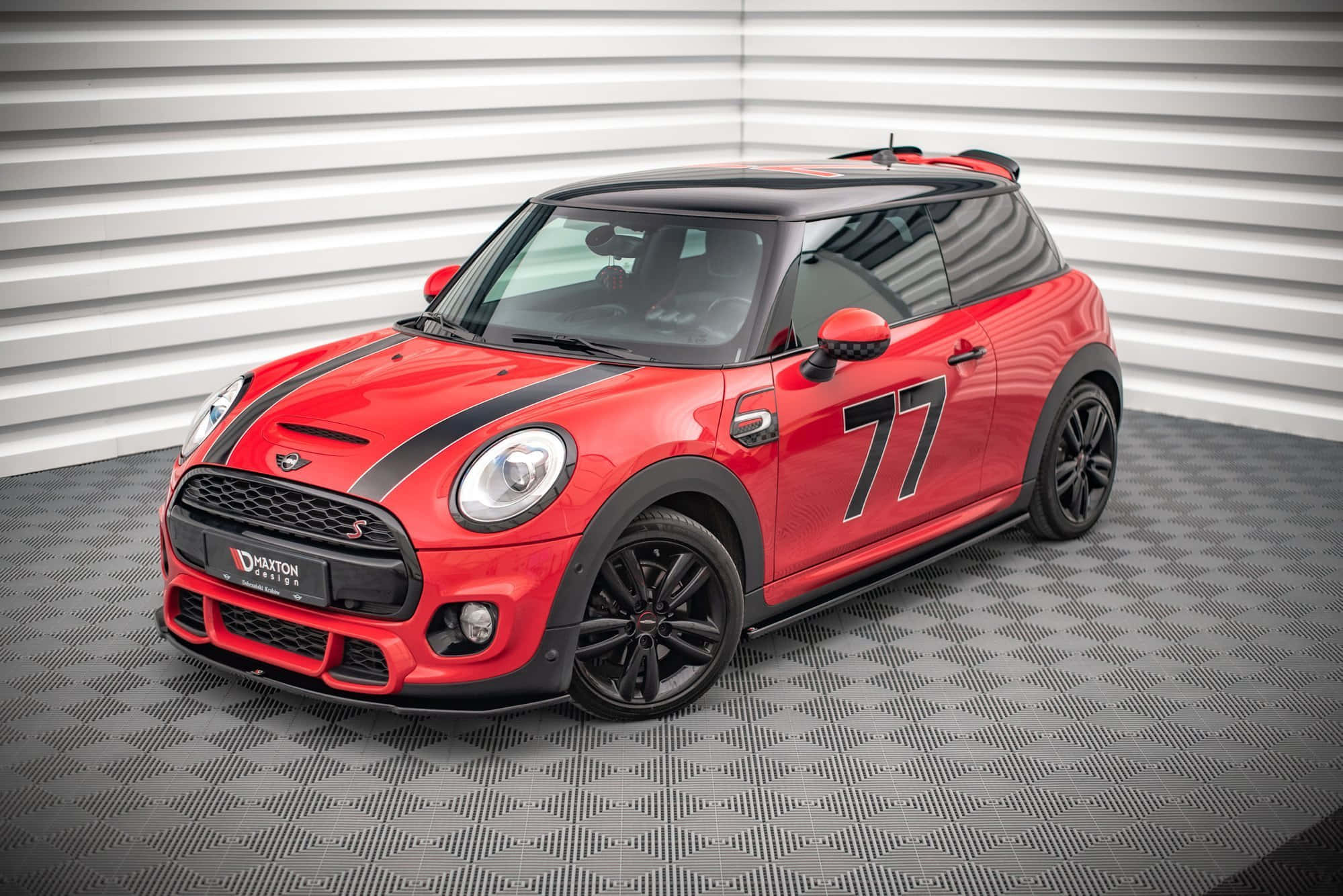 Mini Cooper S 桌布 壁紙 — 一輛充滿活力的紅色MINI Cooper S賽車，帶有黑色飾邊和77號碼，停放在棋盤格地板上，背景是白色波紋牆。
