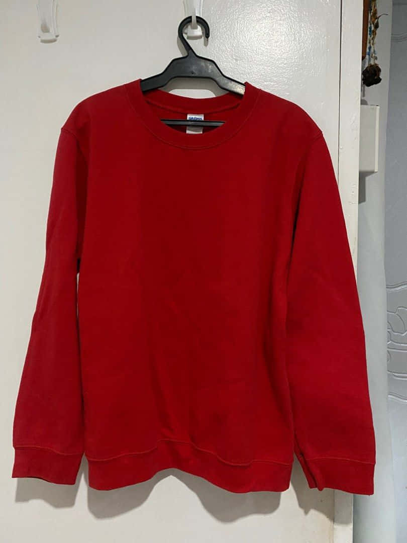 Red Sweater 桌布 壁紙 — 一件鮮紅色連帽衫整齊地掛在黑色衣架上，背景是純白牆壁。