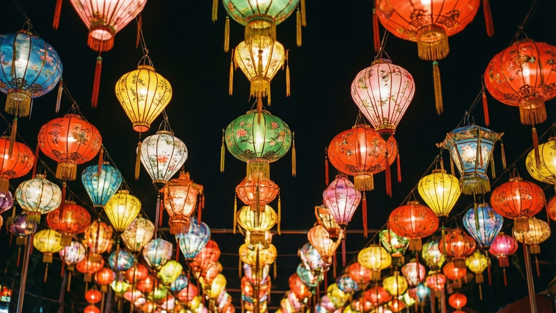 Lantern Festival Night 壁紙 — 色彩鮮豔的傳統燈籠，紅色、藍色、綠色和黃色，在漆黑的夜空中閃耀。