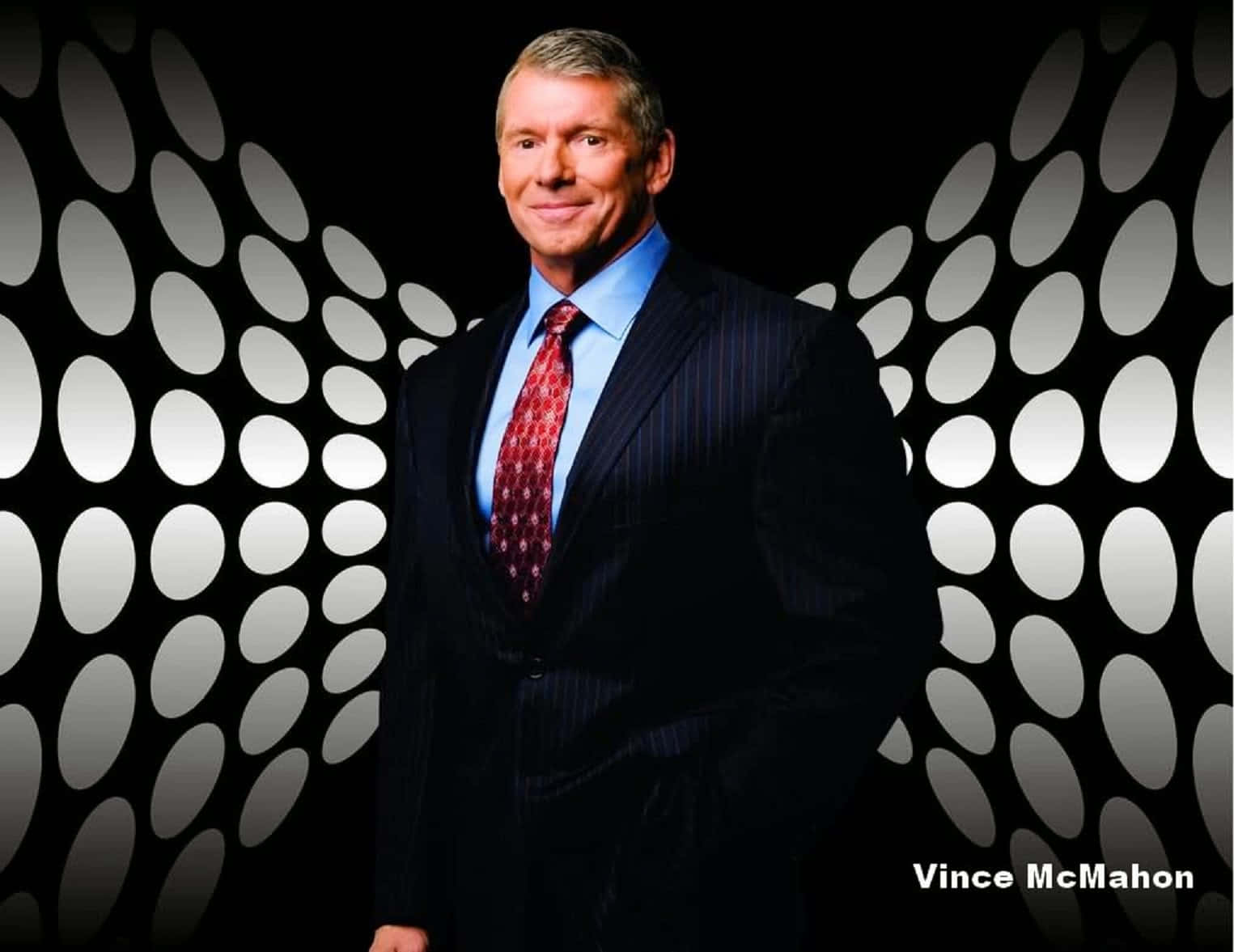 WWE 桌布 壁紙 — Vince McMahon 自信地穿著細條紋西裝，站在帶有發光白色橢圓圖案的黑色牆壁前。