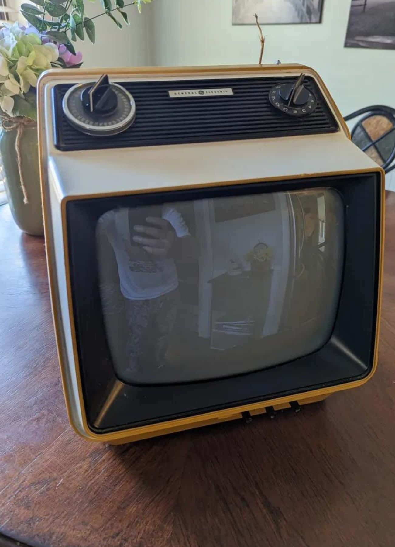 Retro Tv 桌布 壁紙 — 一台復古的米色和黃色通用電氣電視放在木桌上，反射出拍照的人。