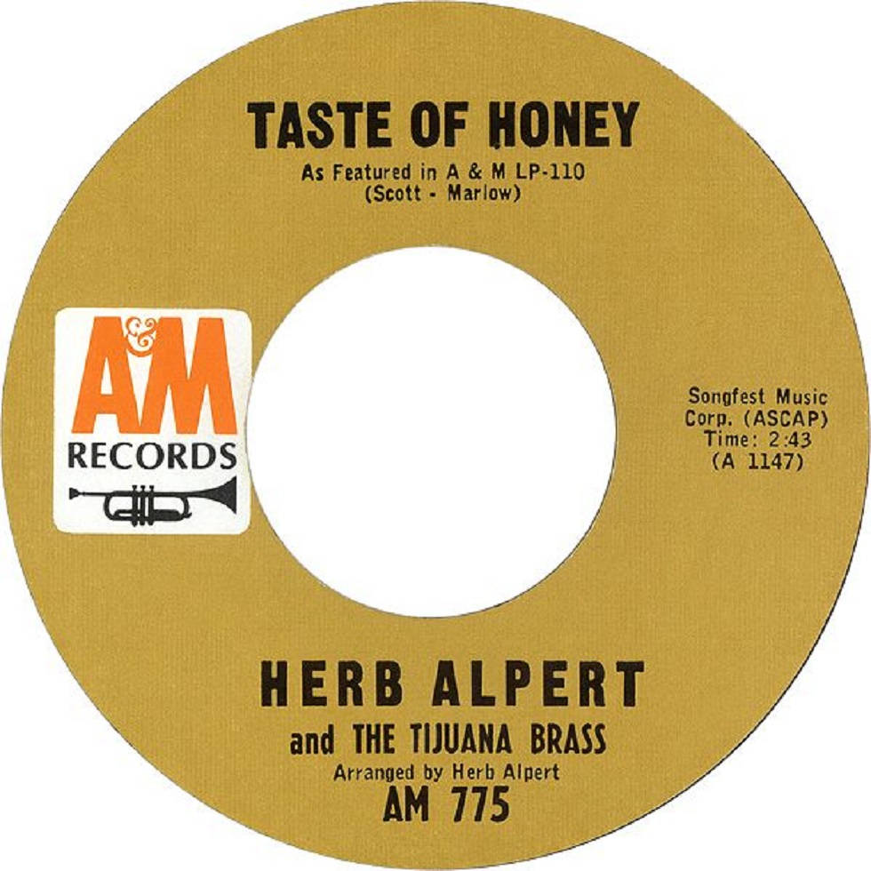 band 桌布 壁紙 — Herb Alpert and The Tijuana Brass 的復古金色黑膠唱片標籤，以粗體黑色文字和 AM Records 標誌呈現「Taste of Honey」。