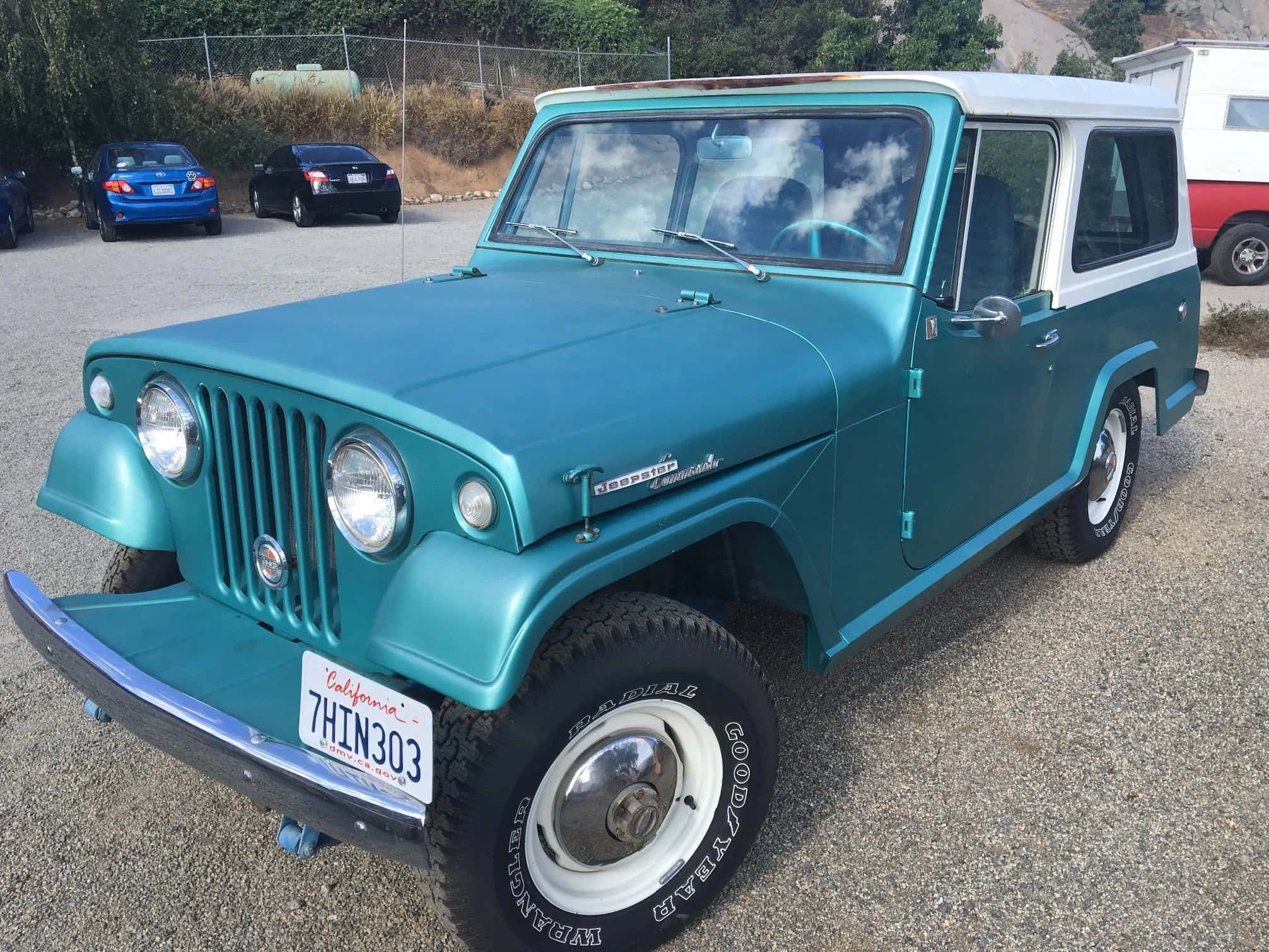 Jeepster 桌布 壁紙 — 一輛復古青綠色和白色的Jeepster Commander停放在碎石上，背景有其他車輛。