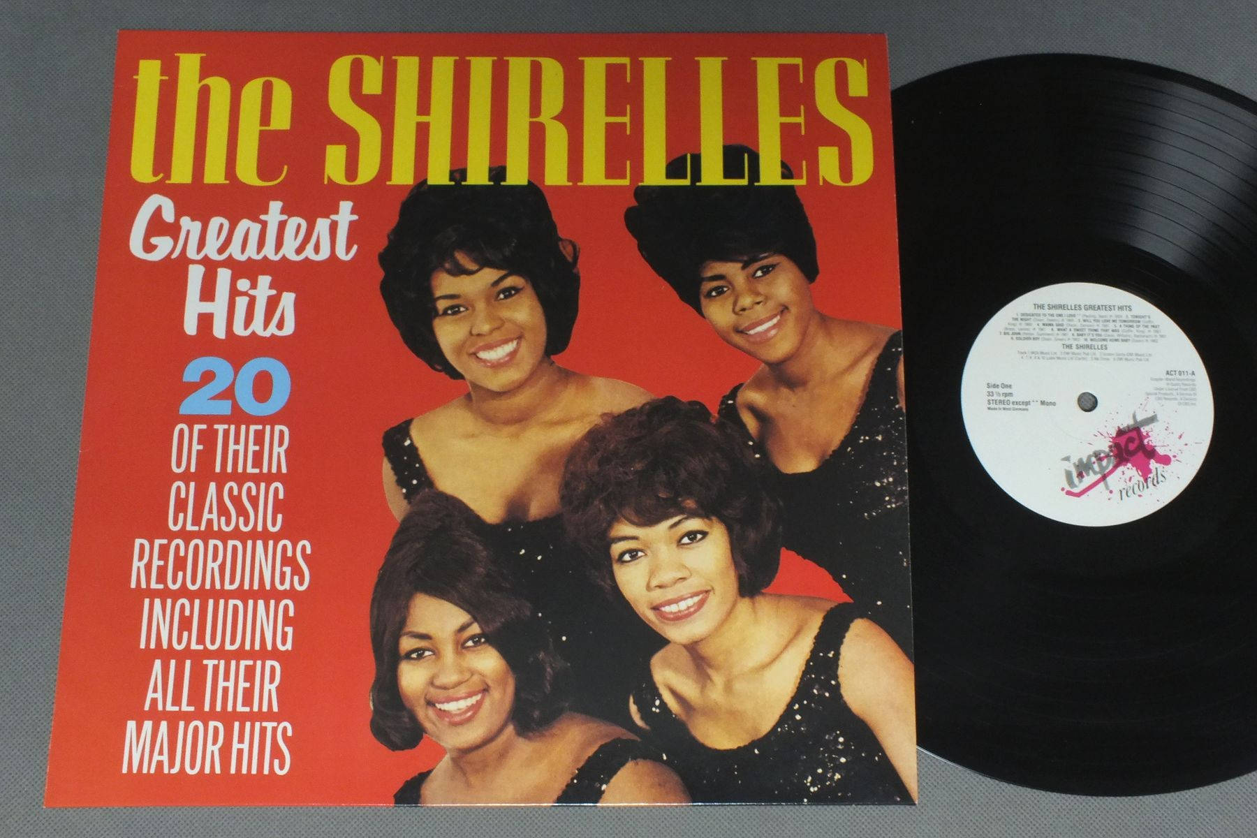 專輯封面 桌布 壁紙 — The Shirelles Greatest Hits 的復古黑膠唱片專輯封面，四位微笑的女性穿著黑色亮片連衣裙，背景為大膽的紅色。