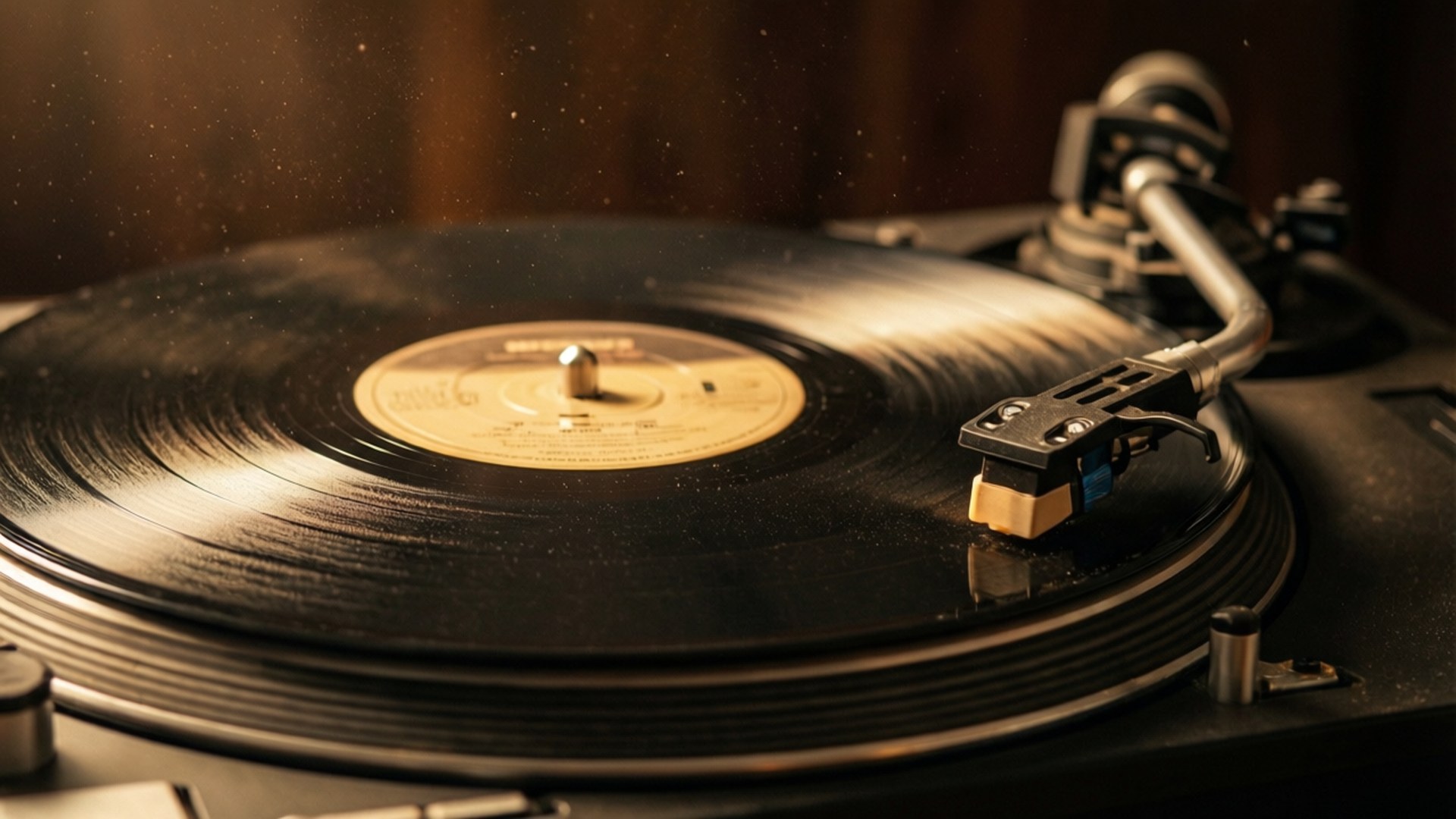 Vintage Vinyl Glow 壁紙 — 一張復古黑膠唱片在溫暖的金色燈光下於唱盤上旋轉，飄浮的灰塵顆粒捕捉著光芒。