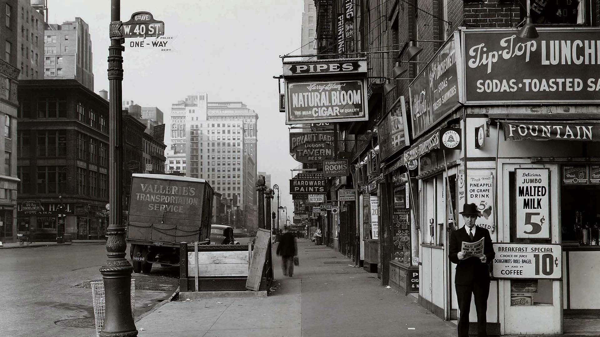 New York 桌布 壁紙 — W 40 St 的復古黑白街景，一名男子在店面和停在路邊的卡車附近閱讀報紙。