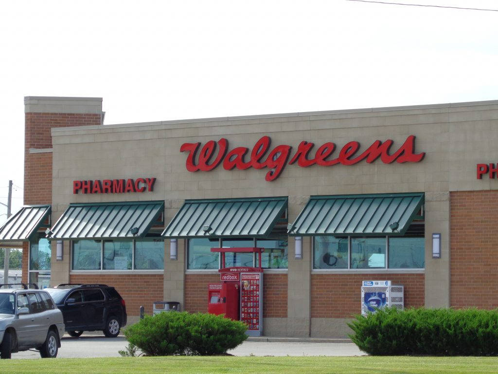 商業 桌布 壁紙 — Walgreens藥店面，紅色招牌、綠色遮陽篷，停泊的車輛，天空多雲。