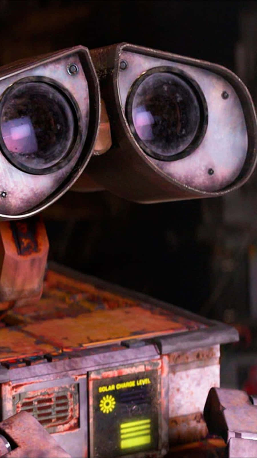 瓦力 桌布 壁紙 — Wall-E 生鏽的雙筒望遠鏡眼睛在昏暗的工業背景下閃爍著好奇心的特寫。