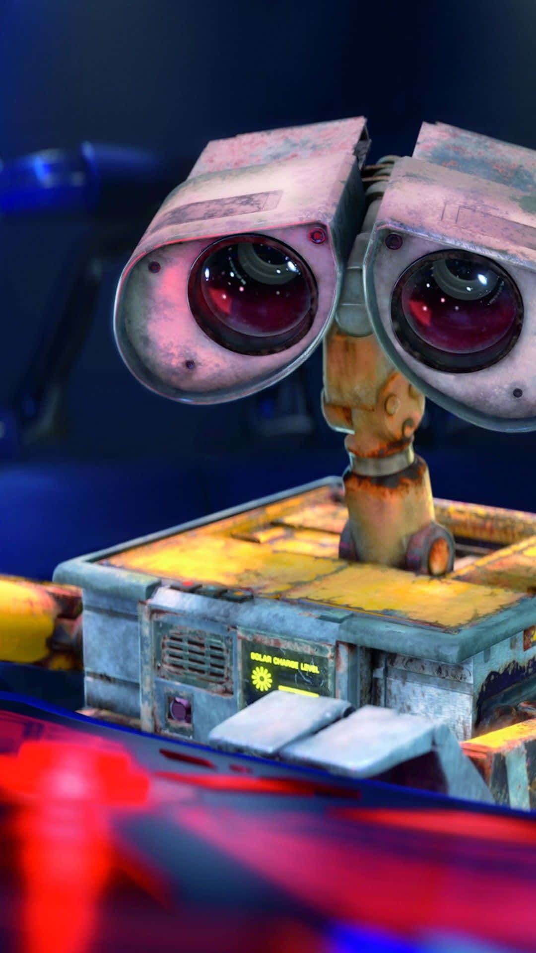 Wall E 桌布 壁紙 — Wall-E 的特寫，擁有大而富有表情的眼睛和生鏽的身體，背景為深藍色，帶有紅色和藍色燈光。