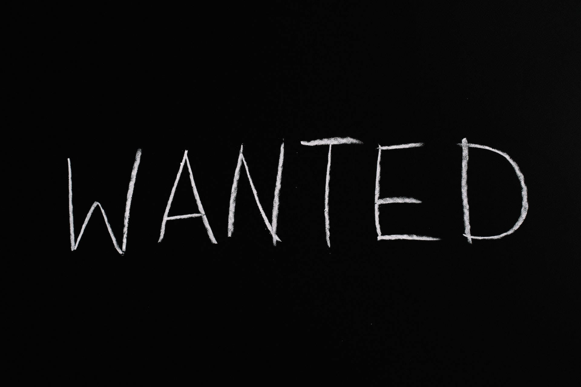 黑色 桌布 壁紙 — 「WANTED」這個字用白色粉筆粗魯地寫在黑板的表面上。