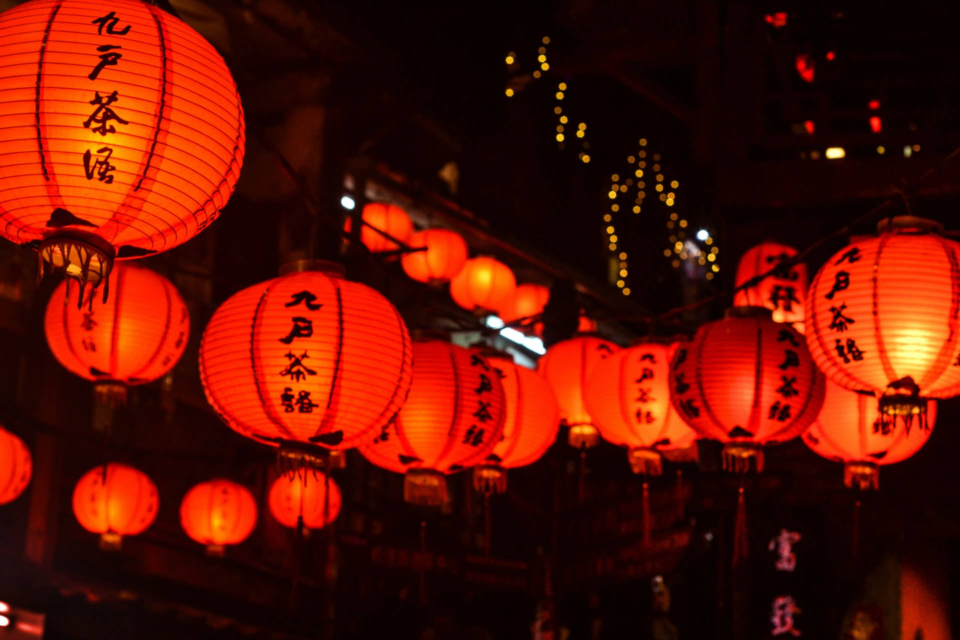 帶有黑色字符的紅色紙燈籠照亮了繁忙的夜晚街道。 — 台北 壁紙