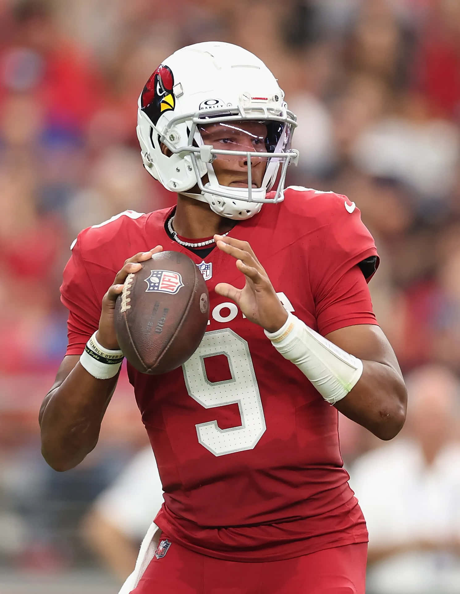  壁紙 — 一位身穿紅色9號球衣、專注的NFL四分衛正在日間比賽中準備傳球。