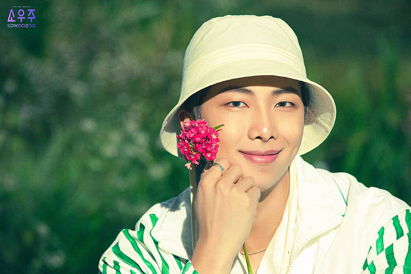 戴白帽的年輕男子手持粉紅花在戶外微笑 — Bts 壁紙