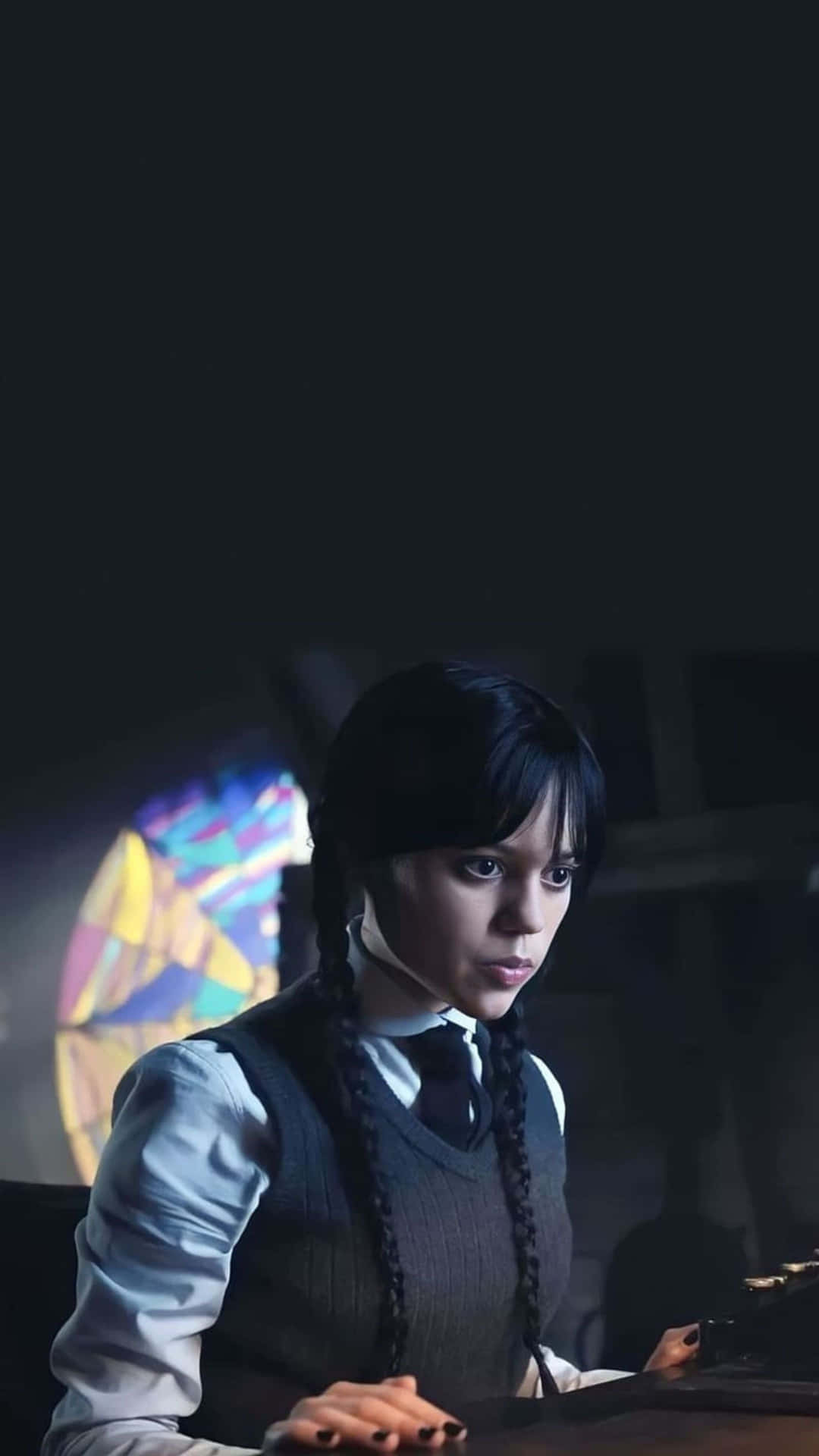  壁紙 — 一位年輕女性，梳著黑色辮子，穿著哥德式服裝，坐在昏暗的房間裡，身後有色彩繽紛的彩繪玻璃窗發光。