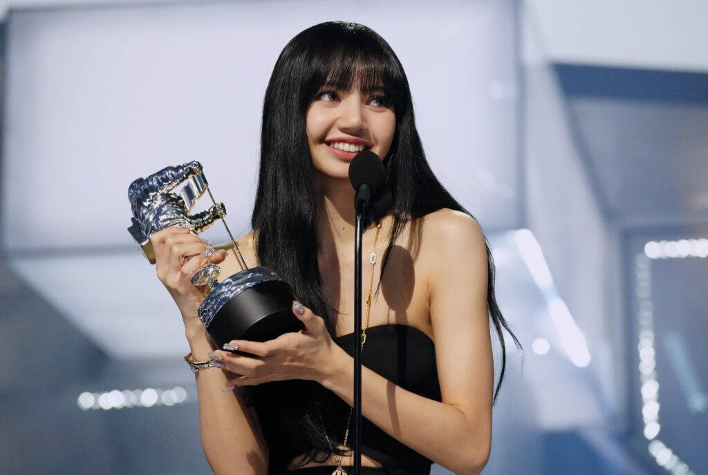 女性在舞台上手持獎項並微笑，旁邊有麥克風。 — Blackpink 壁紙