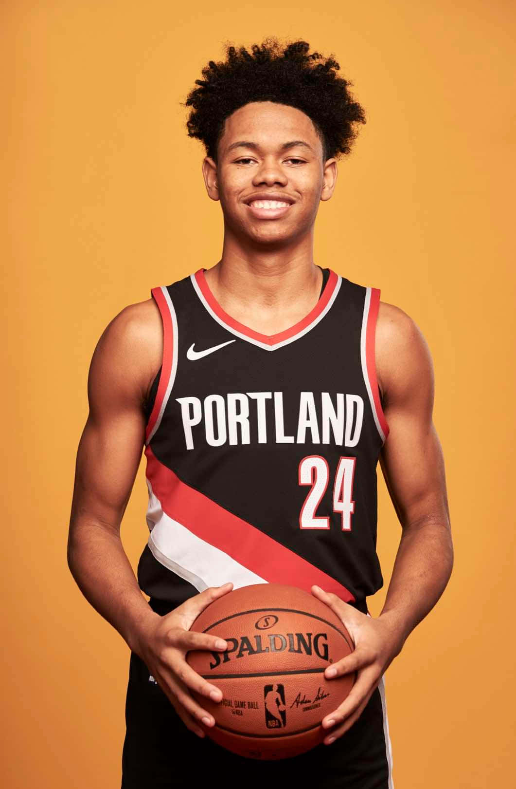 身穿波特蘭球衣的年輕籃球運動員拿著一個Spalding籃球。 — NBA 壁紙