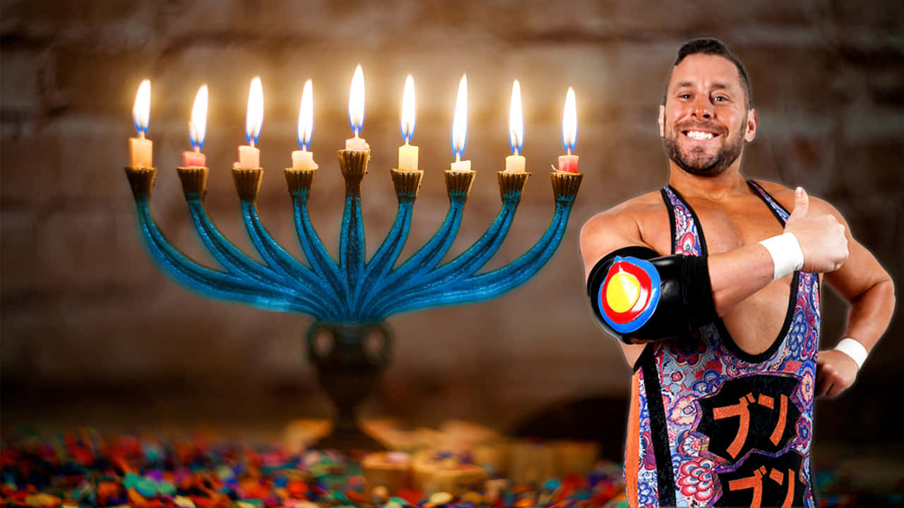  壁紙 — 一位微笑的摔角手身穿色彩繽紛的服裝，在發光的藍色 menorah 旁邊豎起大拇指，menorah 上有九支點燃的蠟燭。