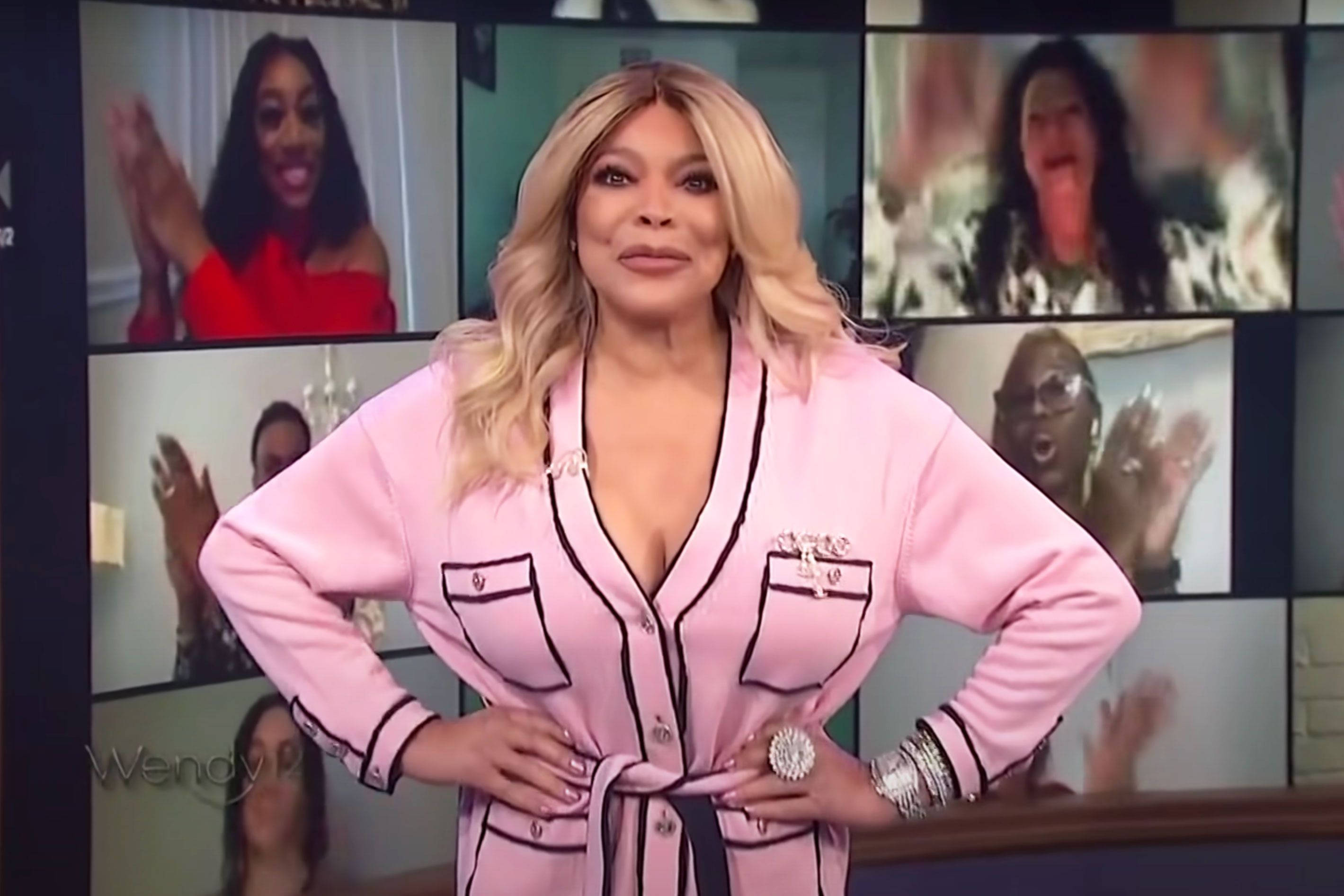 Celebrity 桌布 壁紙 — Wendy Williams 自信地穿著帶黑色飾邊的粉紅色長袍，身後的多個視頻螢幕顯示著歡呼的人群。