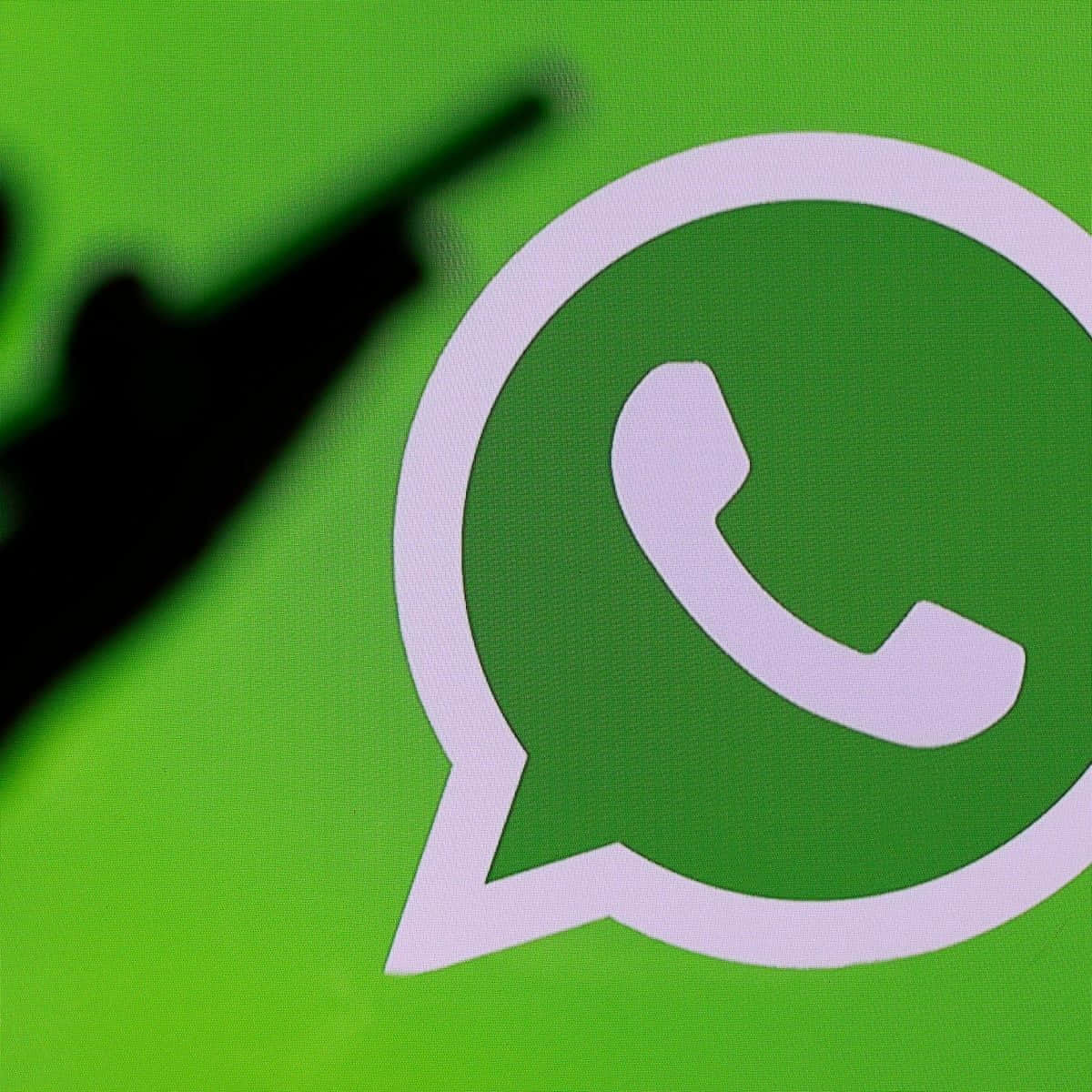 WhatsApp 桌布 壁紙 — WhatsApp 標誌的特寫，背景有一個模糊的黑色手指指向剪影。
