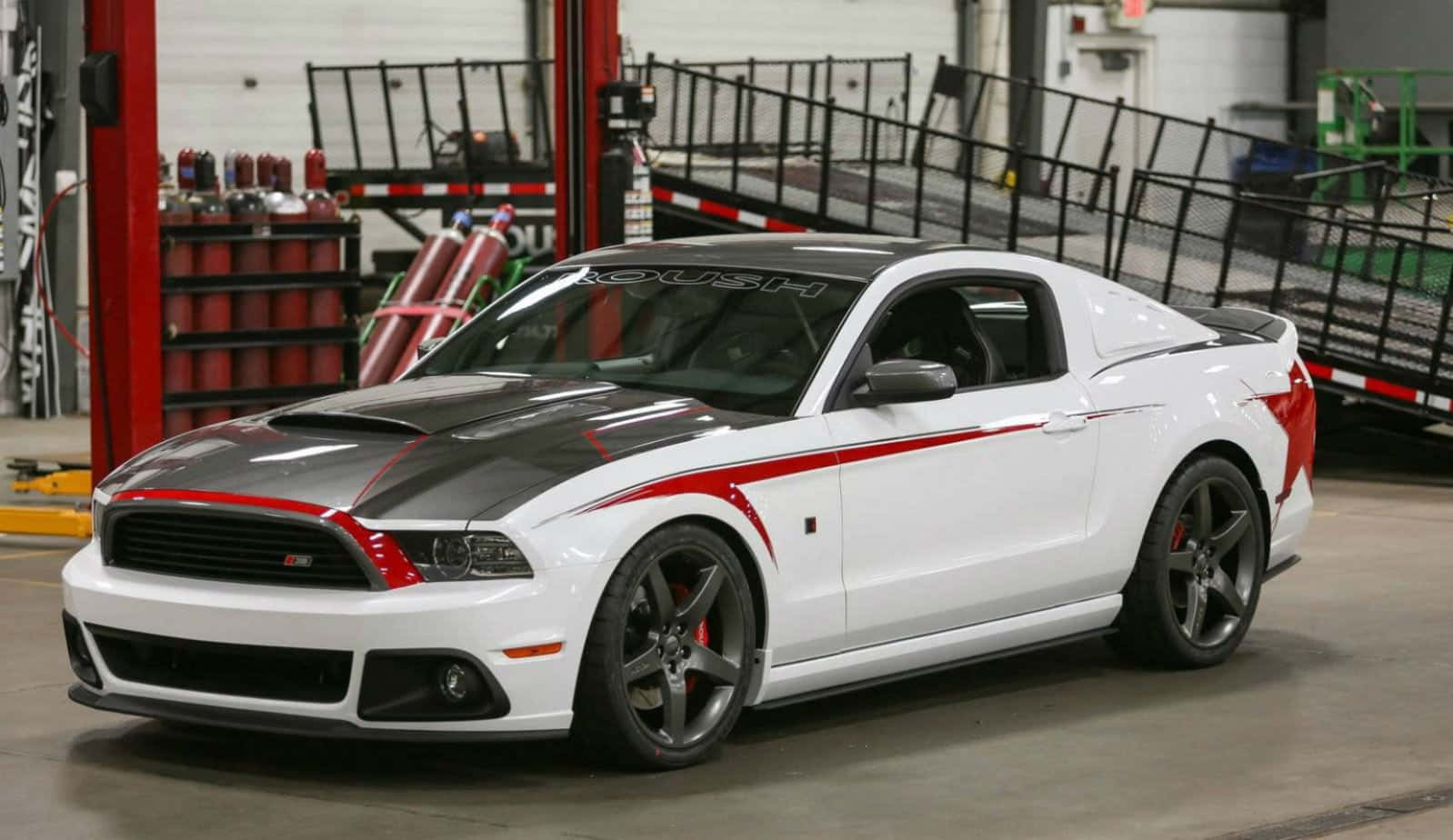 Ford Mustang Roush 桌布 壁紙 — 一輛帶有紅色點綴的白色和黑色福特野馬Shelby GT500停放在光線充足的車庫中，周圍是汽車設備。
