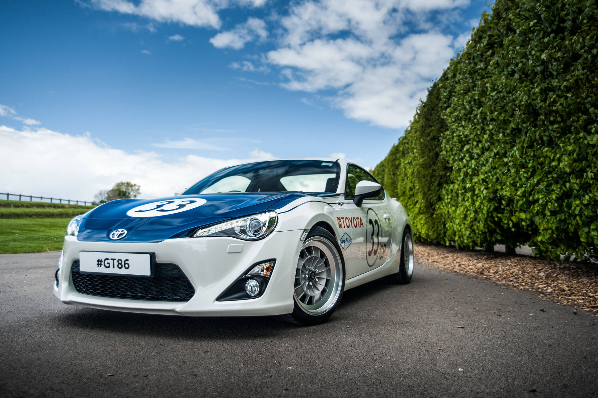 晴朗日子裡，白色和藍色的豐田GT86賽車停在綠色籬笆旁。 — Toyota Supra 壁紙